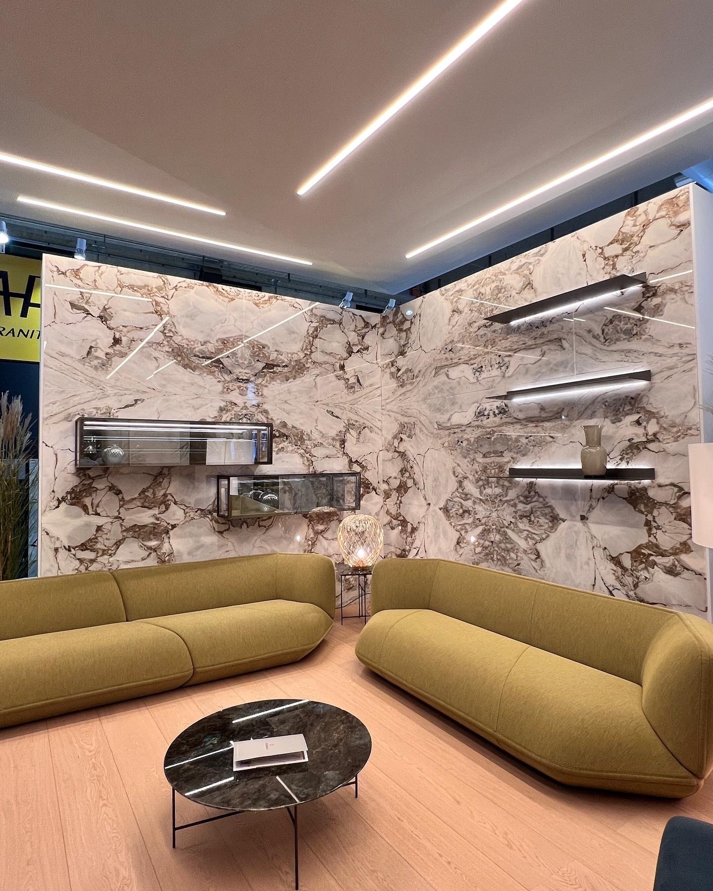 Salotto moderno con divani gialli, parete di marmo decorativa, tavolino rotondo nero, e illuminazione a LED. arch-12 A-12  Simone Rosi design