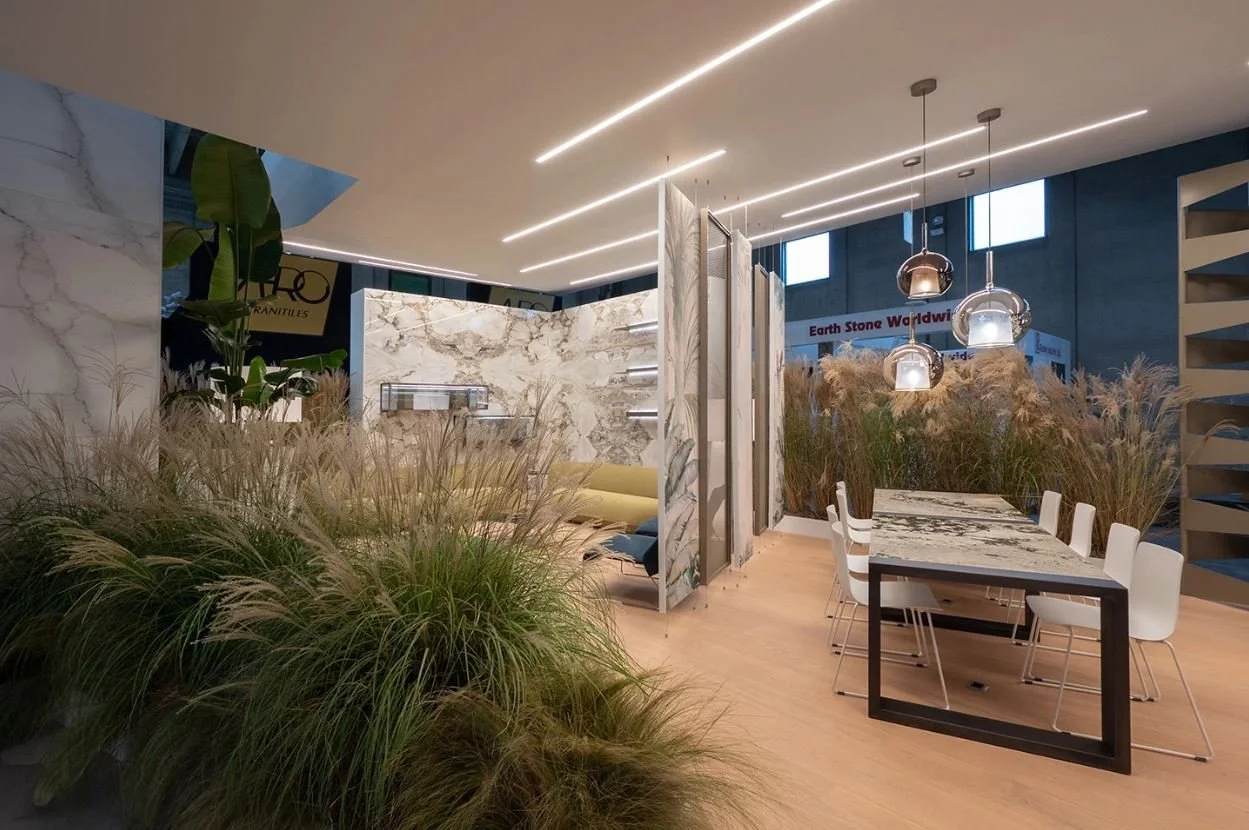 Studio di design d'interni con mobili moderni, tavolo e sedie bianche, divisori in marmo e decorazioni con piante e luci a sospensione. arch-12 A-12  Simone Rosi design