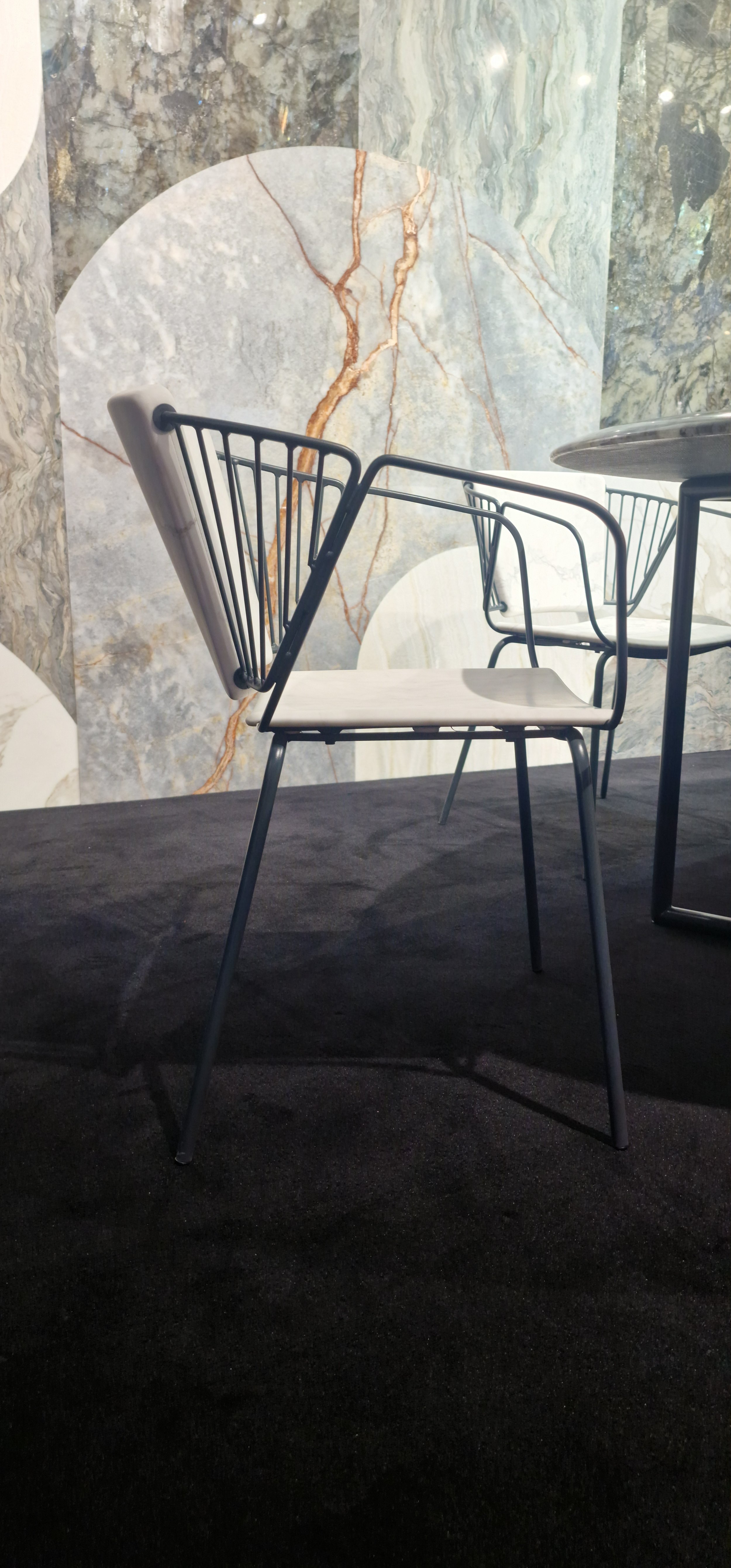 Sedia moderna con struttura in metallo e seduta chiara, su sfondo di pareti con marmo a vista.arch-12 A-12 Simone Rosi design Monaco Yacht Show menchini marmo Arch-12 - A-12-Simone Rosi design