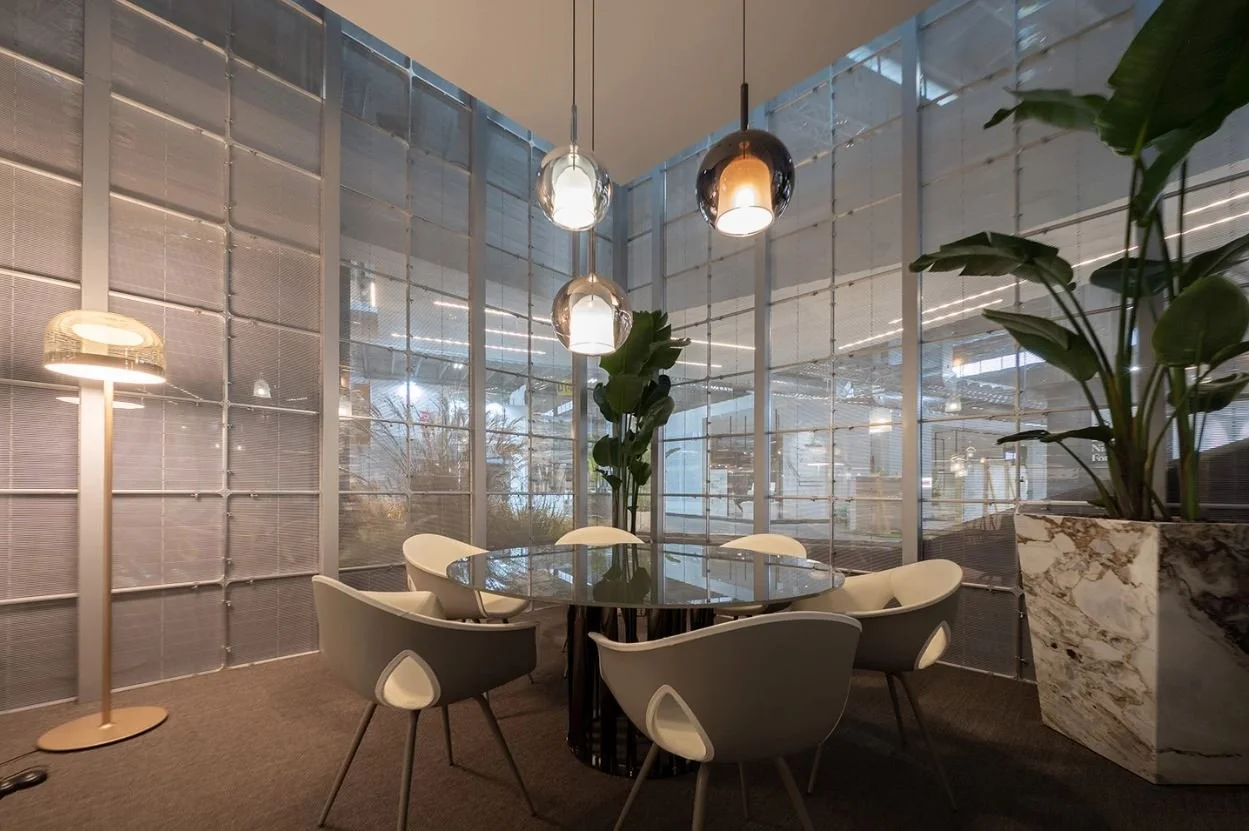 Ufficio moderno con tavolo rotondo di vetro, sei sedie, lampade sospese, grande pianta in vaso e pareti trasparenti divisorie. arch-12 A-12  Simone Rosi design