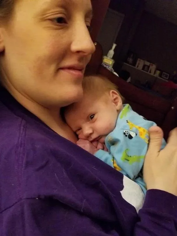 Young mother holding a newborn baby on her chest