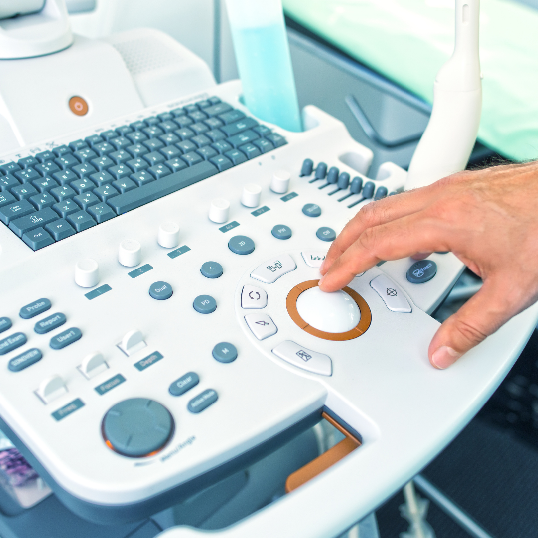Medical ultrasound machine with a hand adjusting controls.