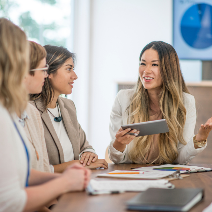Business meeting with four women discussing data and charts.