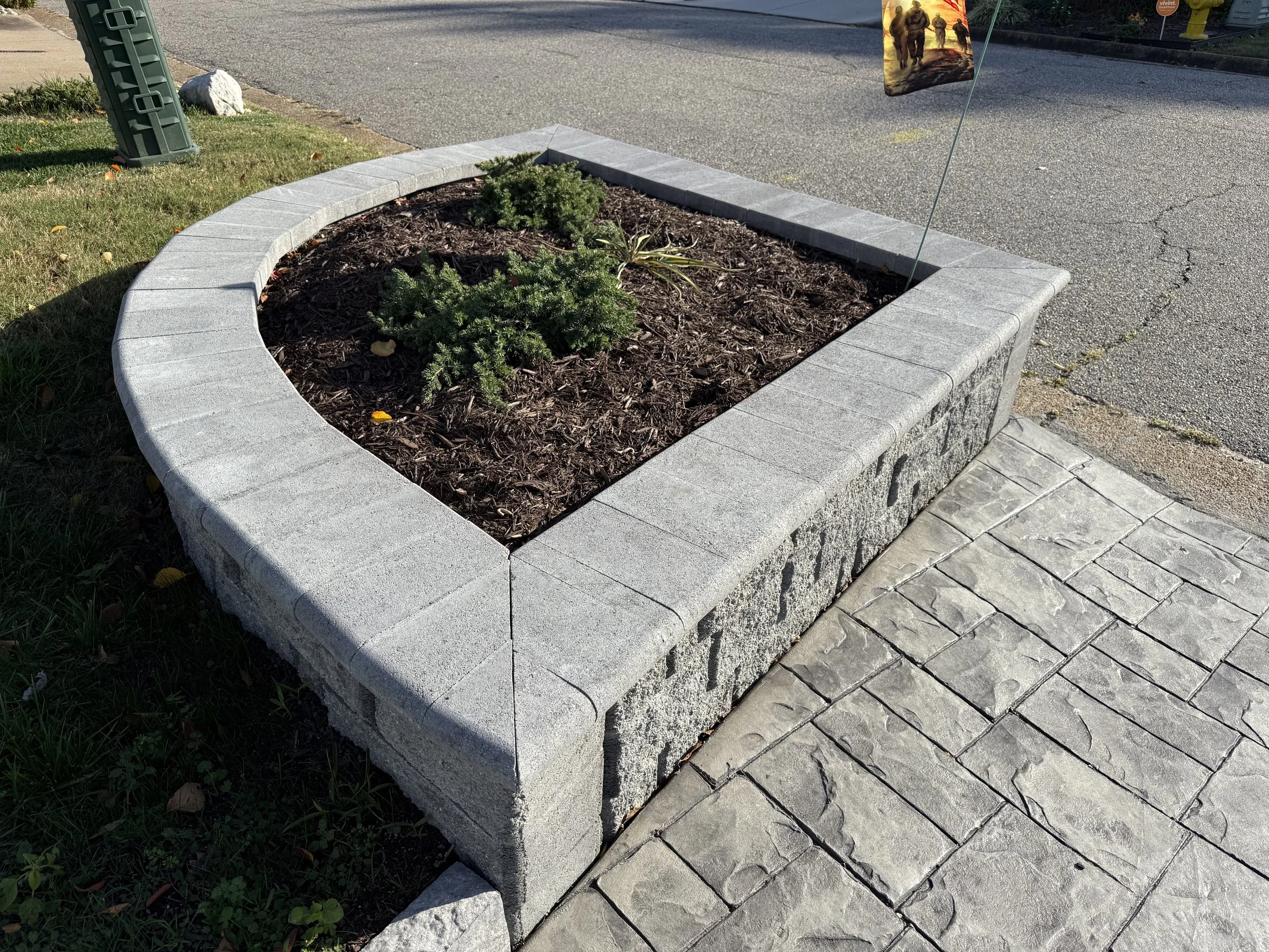 After — We removed the pre-existing concrete, rebuilt the wall with modular blocks and a capstone, and finished with new plantings.