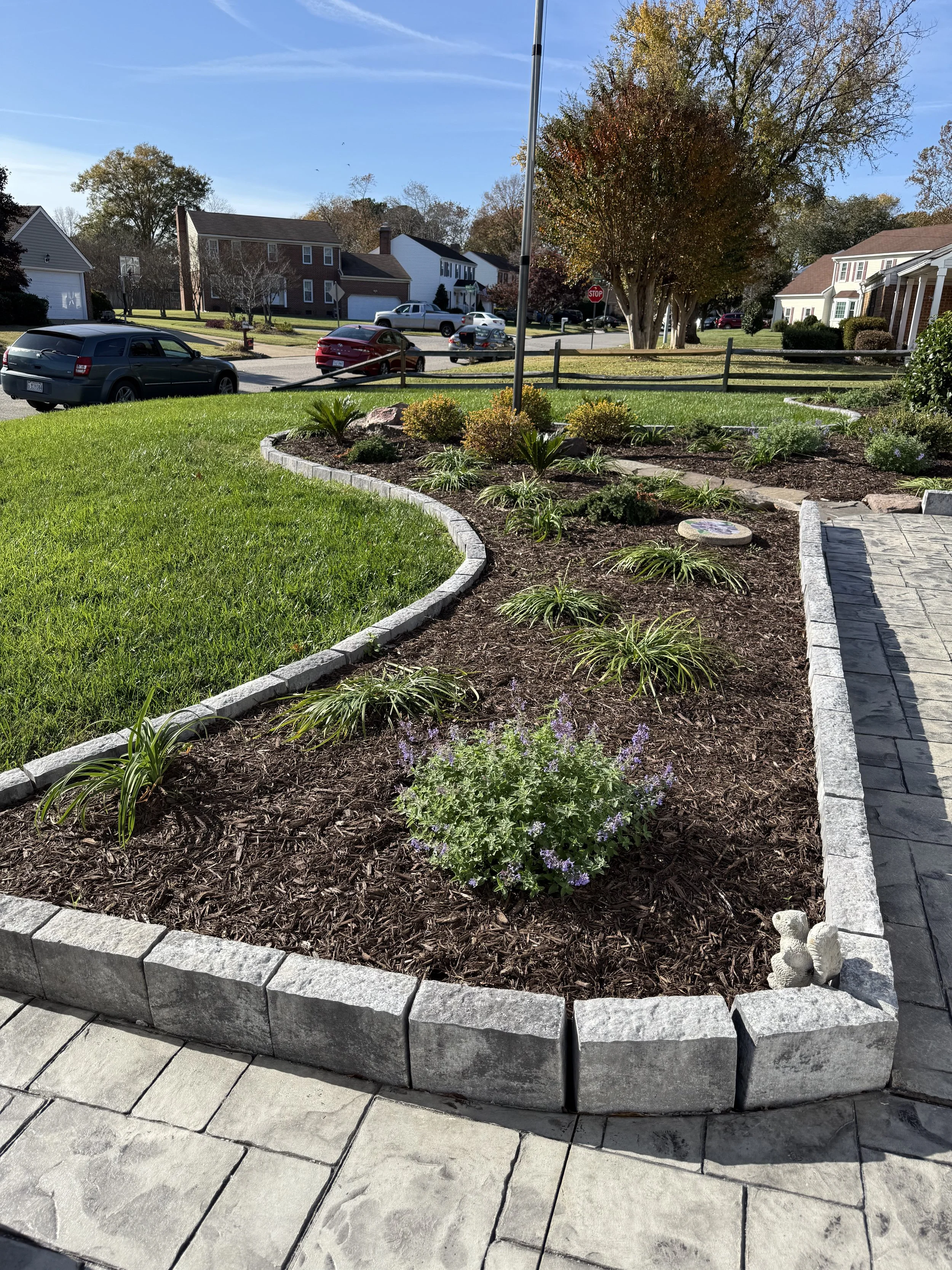 After — Stone edging installation, soil prep, plant installation, and a clean mulch finish.