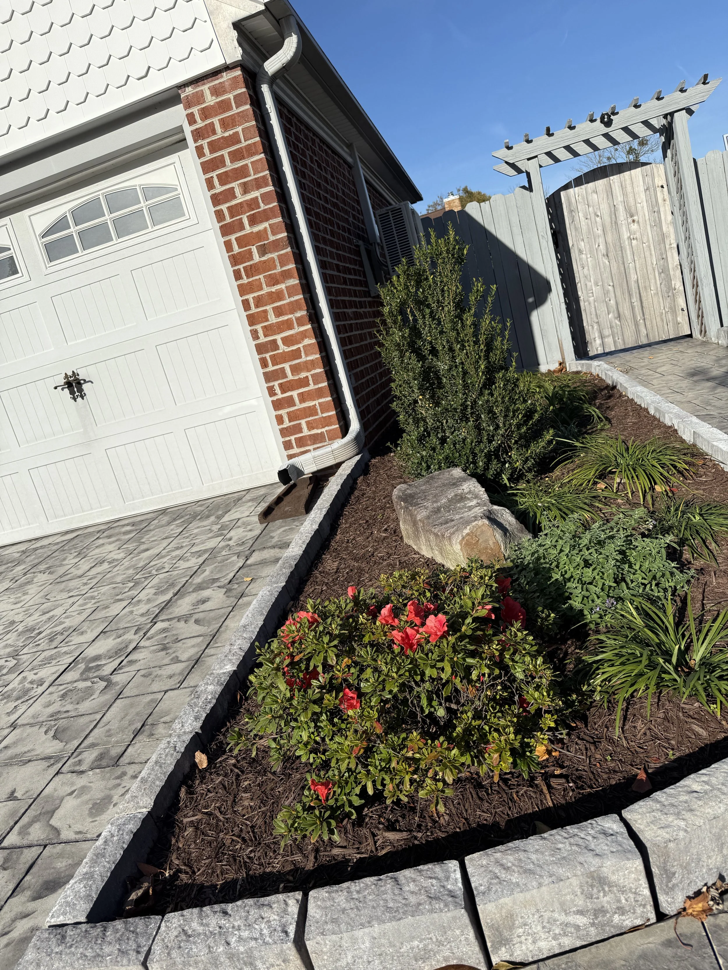 After — Stone edging installation, soil prep, plant installation, and a clean mulch finish.
