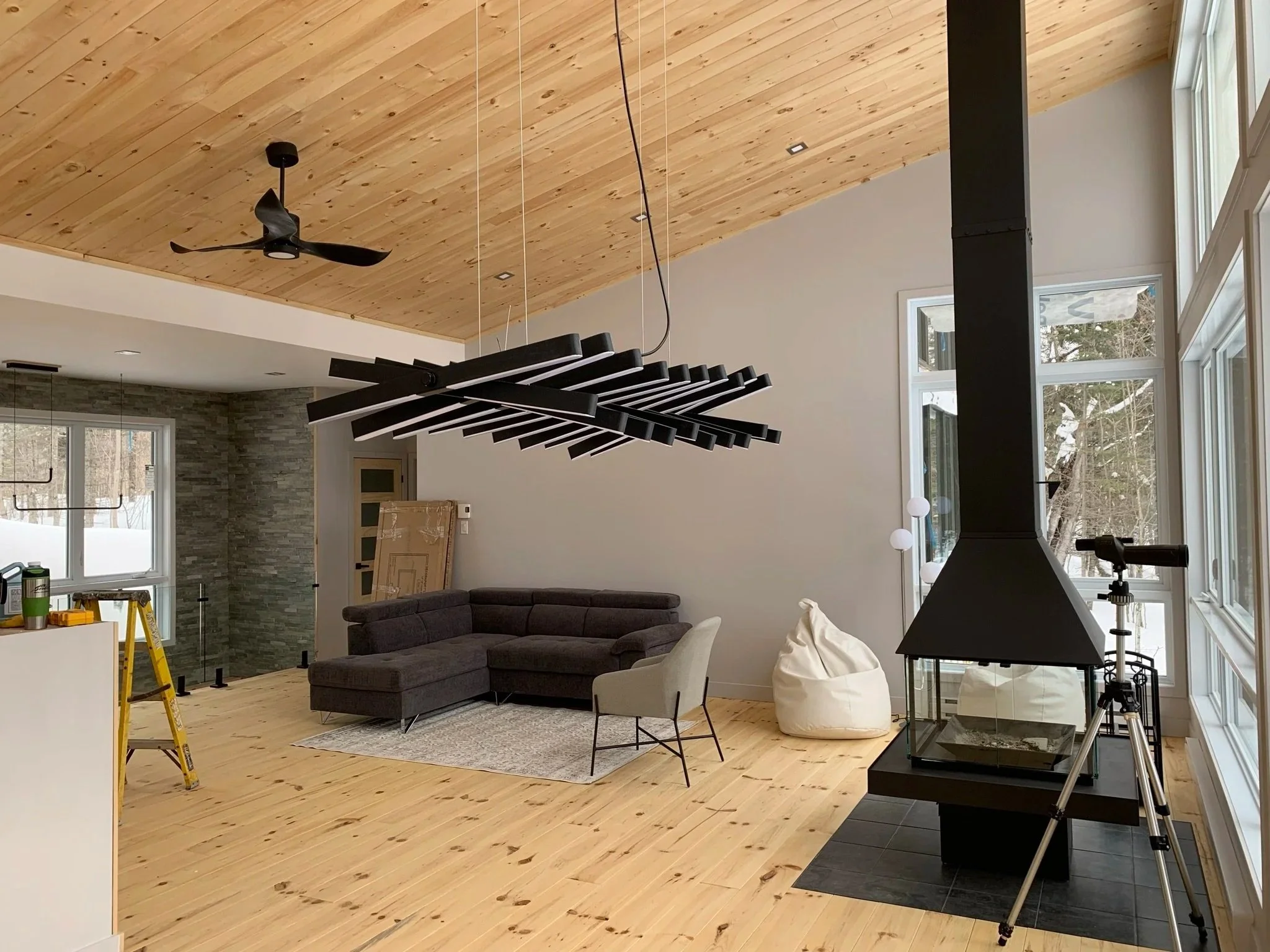 Salon avec boiserie au plafond et plancher, avec mur de pierre décoratif avec vue panoramique sur la montagne