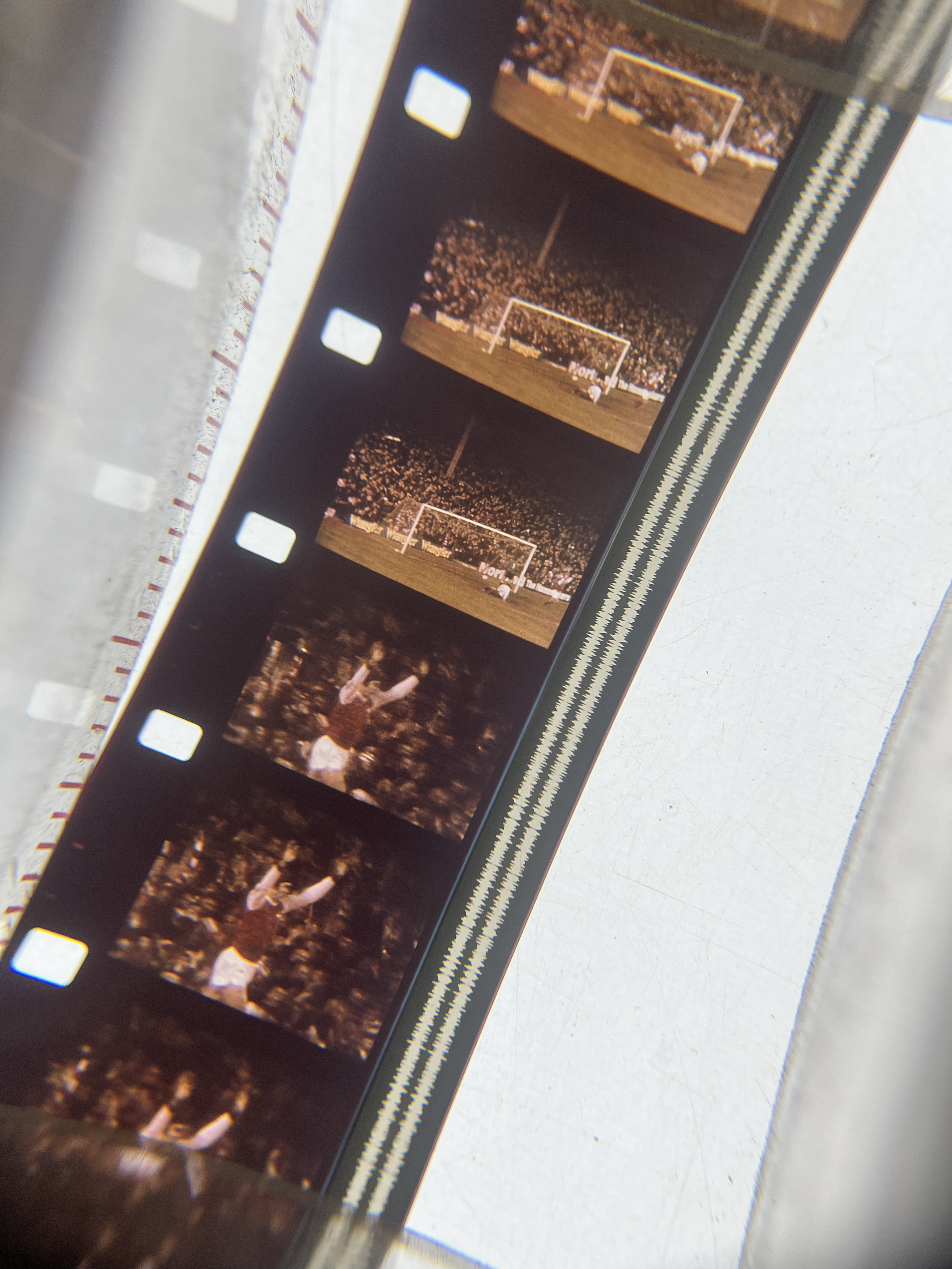 Photo of a 16mm filmstrip showing multiple frames of a 1976 Arsenal FC match, including a goal and a player celebrating.