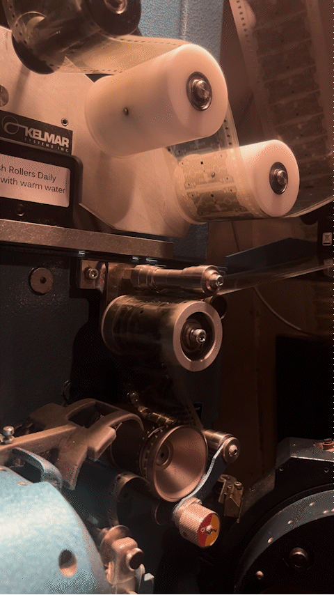 Close-up of a film projector with reels of film, gears, and mechanical components.