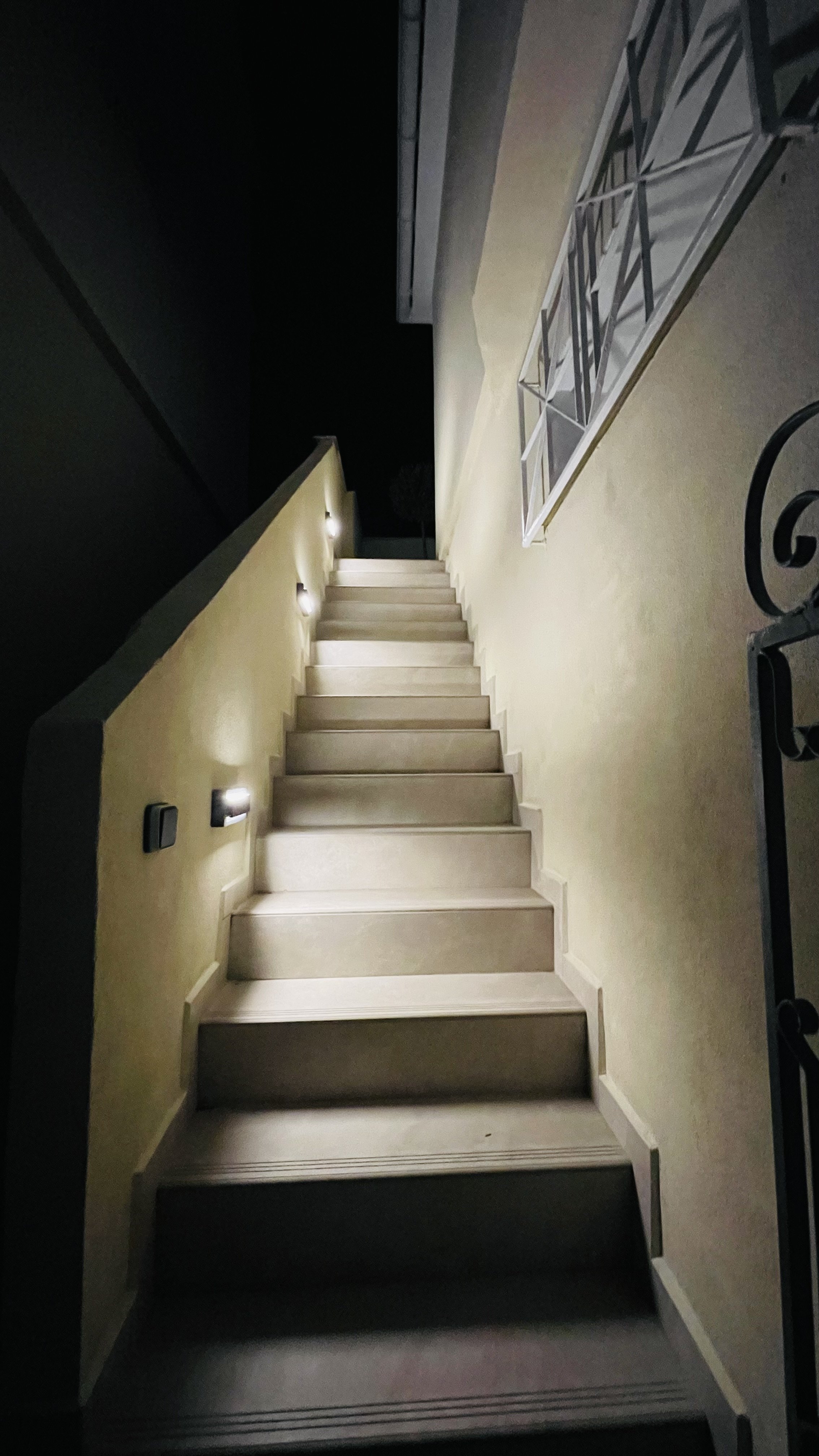 Outdoor staircase at night with wall-mounted lights