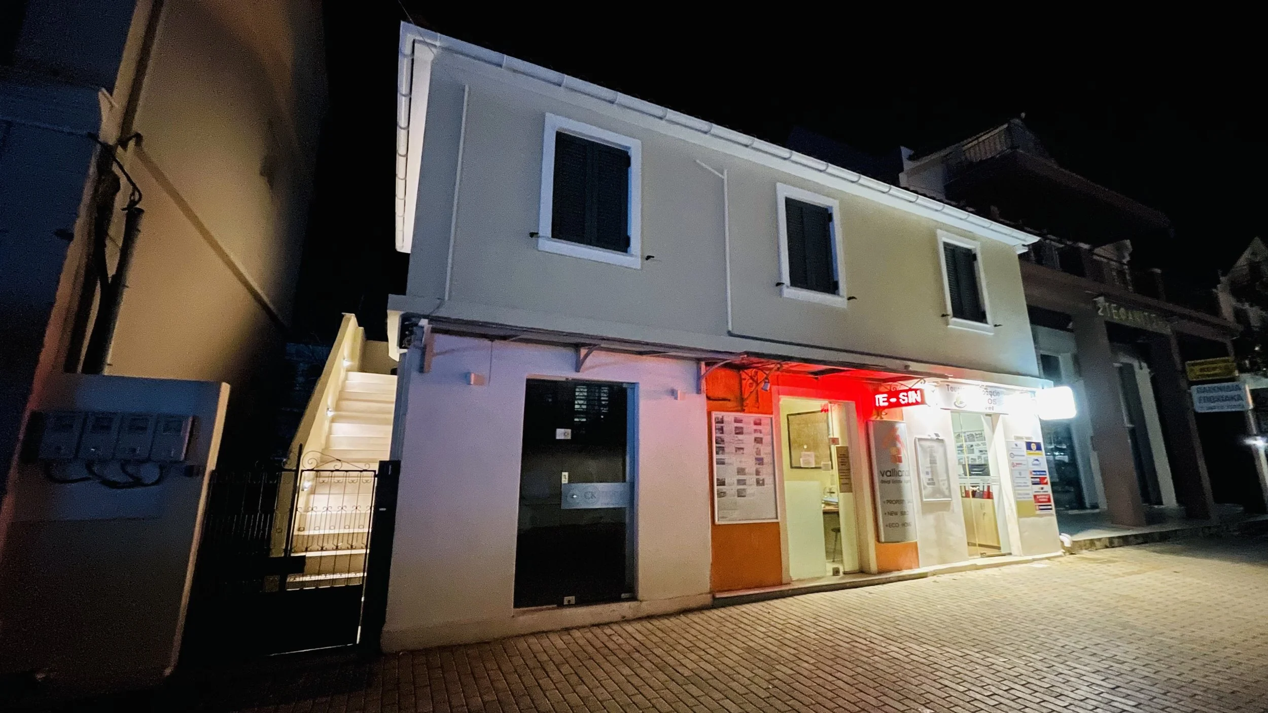 Building exterior at night with illuminated signs and staircase