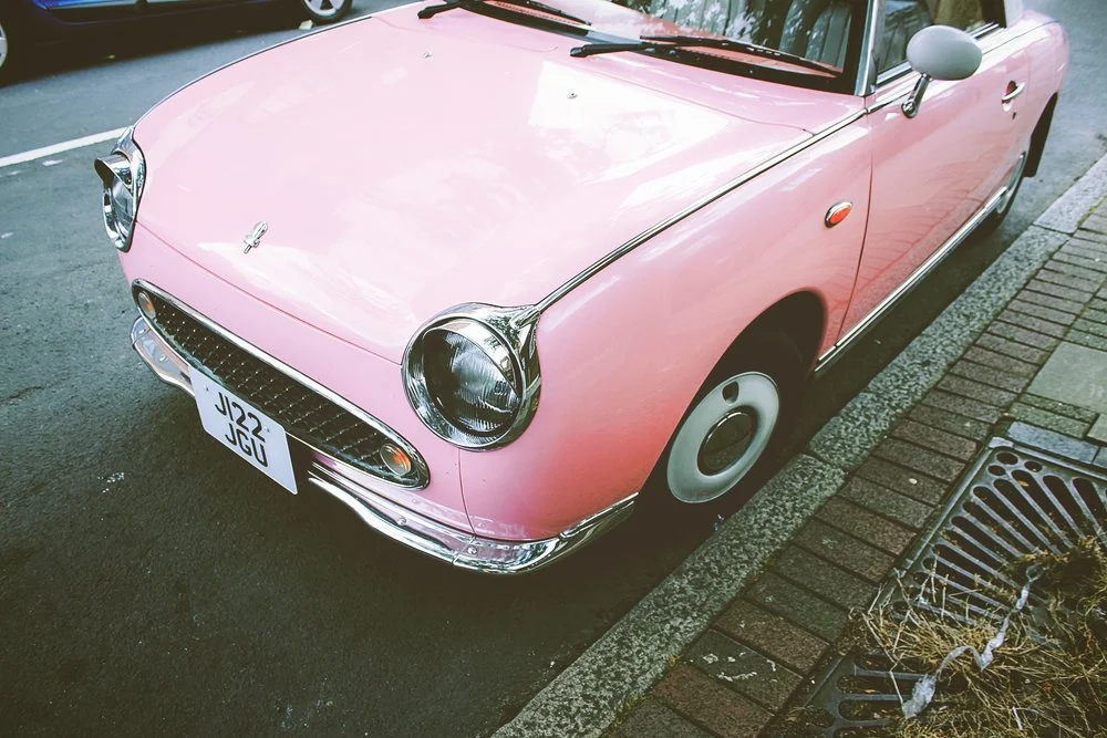 Pink vintage convertible car parked on the street.