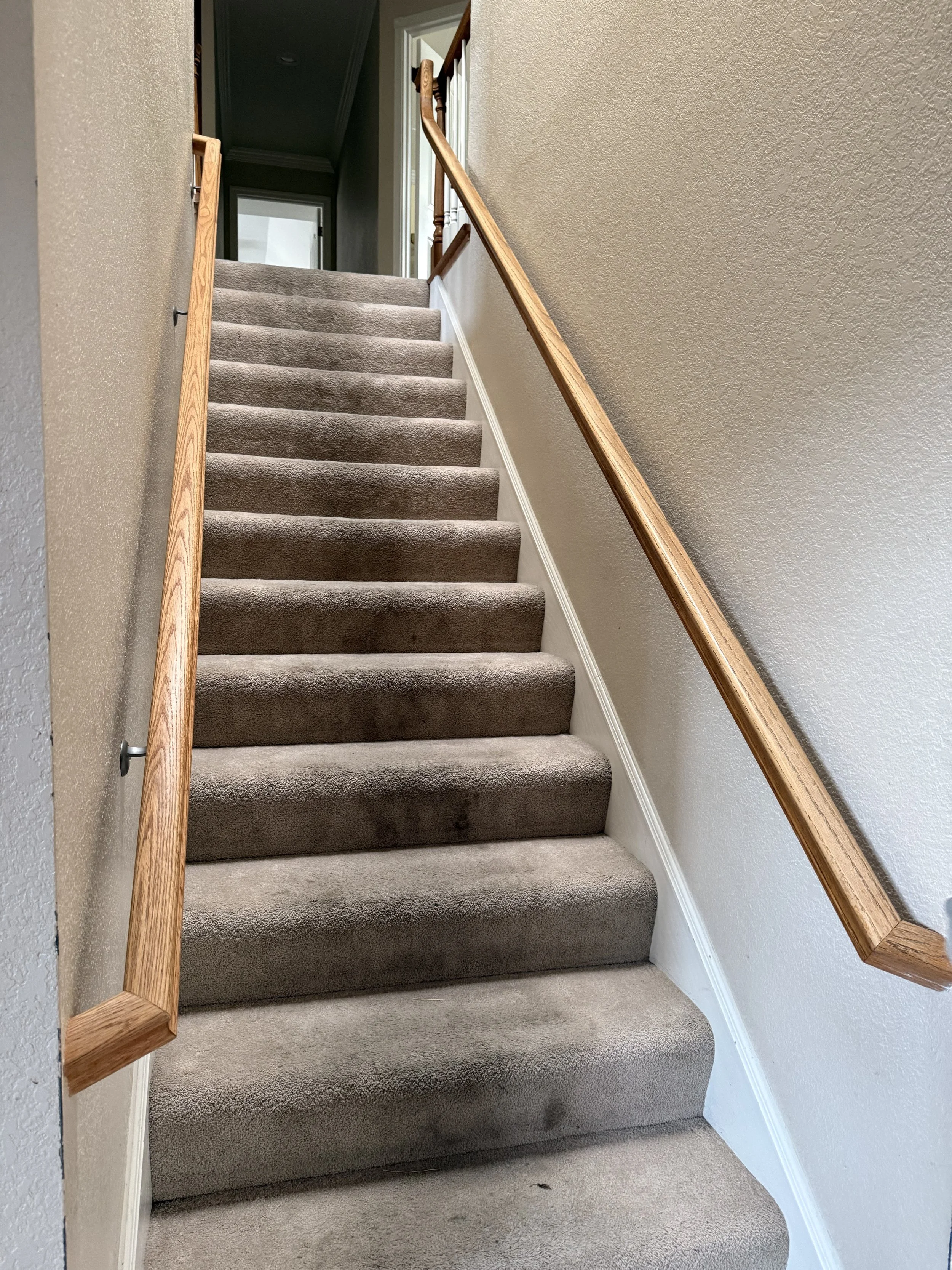Carpeted staircase with new wood handrail