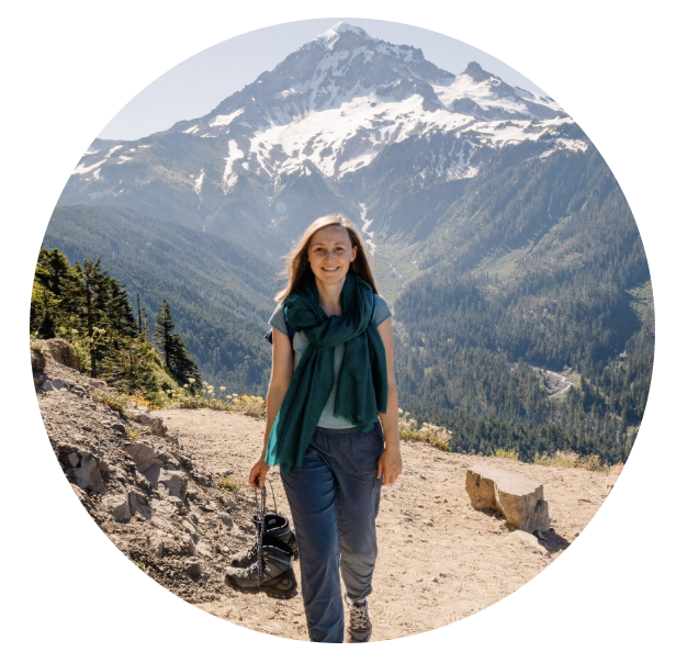 A woman walking on a path with a snow capped mountain behind her