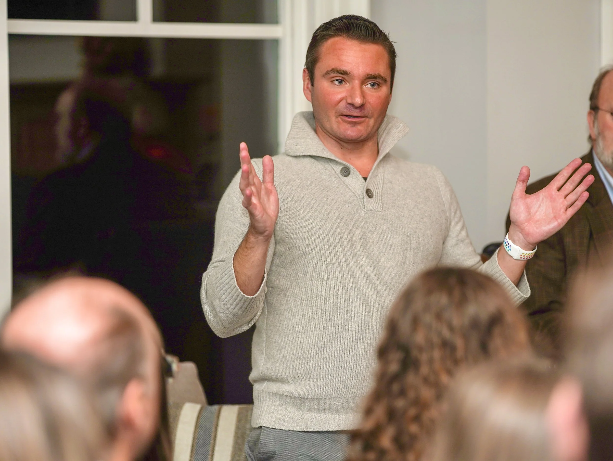 A man speaking to a group of people indoors.