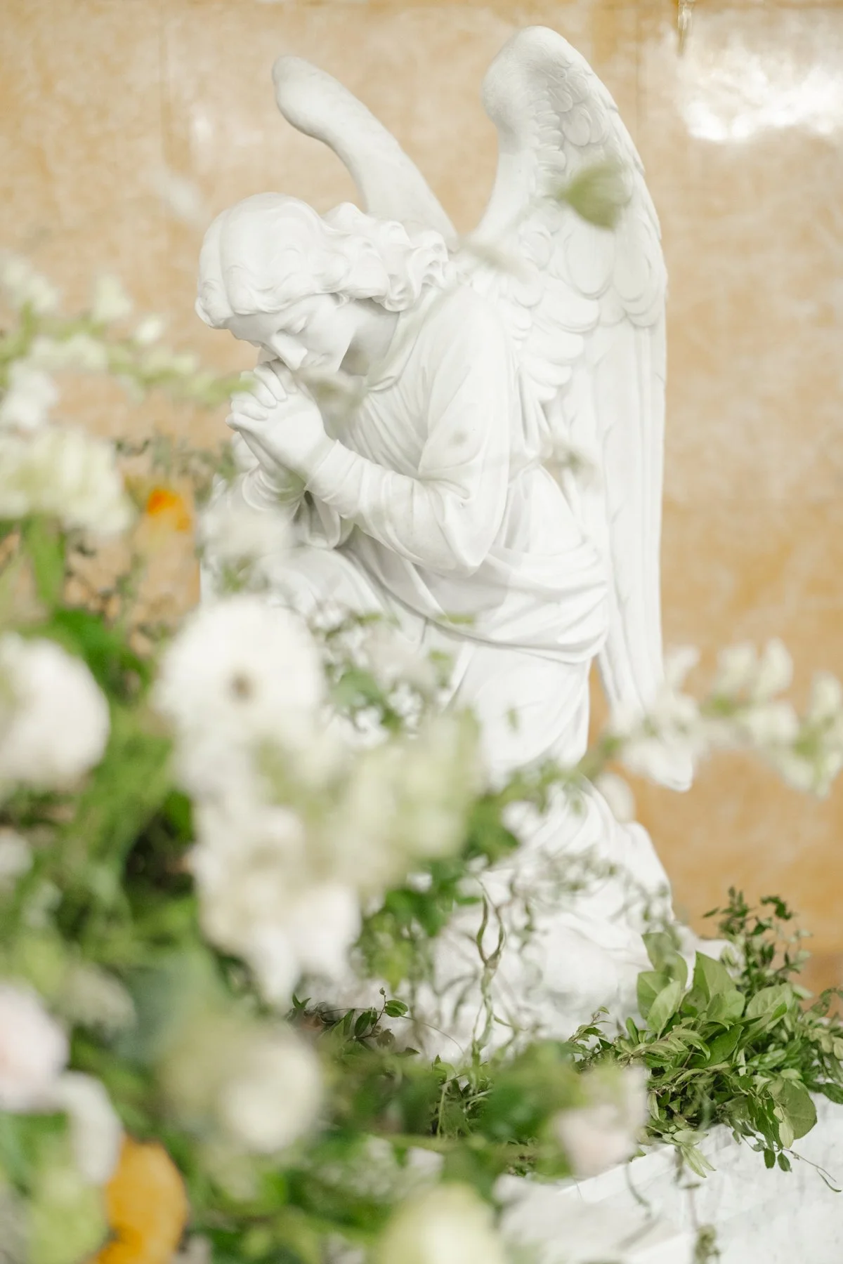 Angel statue surrounded by fresh floral arrangements inside a decorated church — elegant flower display for religious ceremonies, weddings, or memorial services