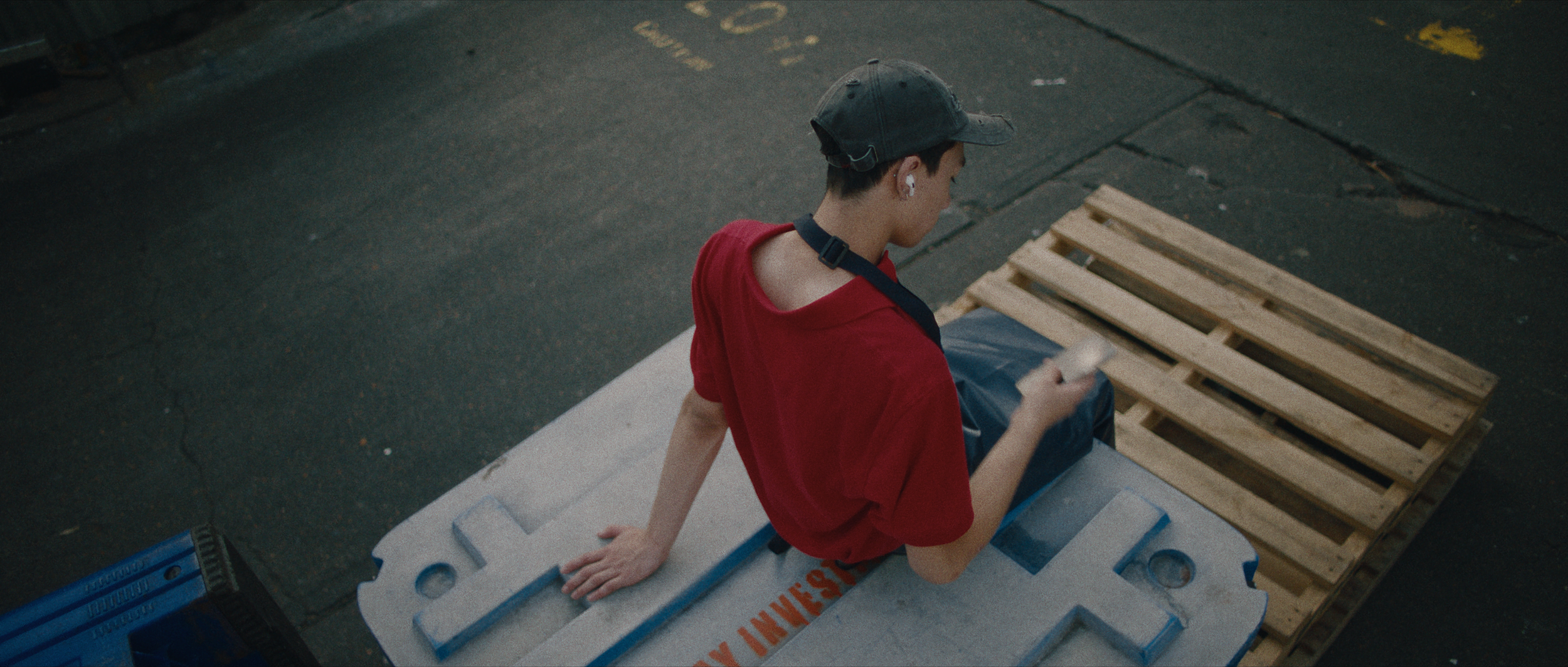 Emery Kaison sitting on pallets with phone in I'll Be There For You music video.