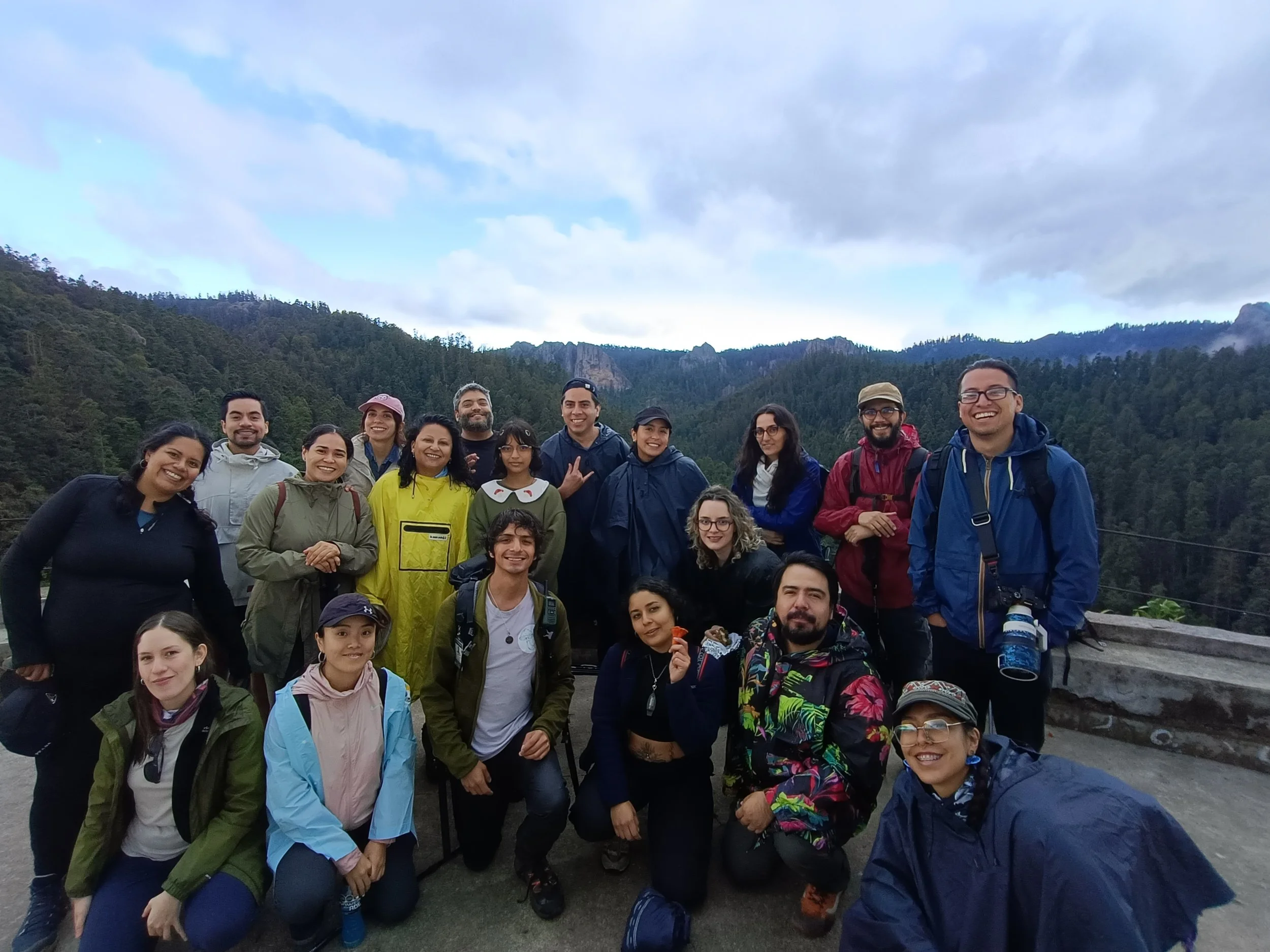 Grupo de personas con mochilas en una vista de montaña, en un día nublado.