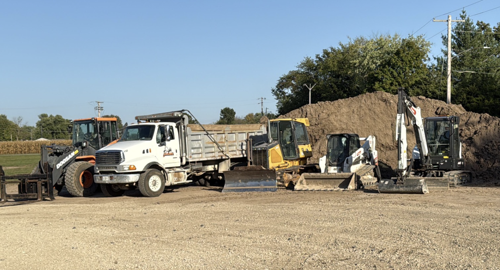 Construction site with a dump truck and three excavators working on dirt and earthmoving.