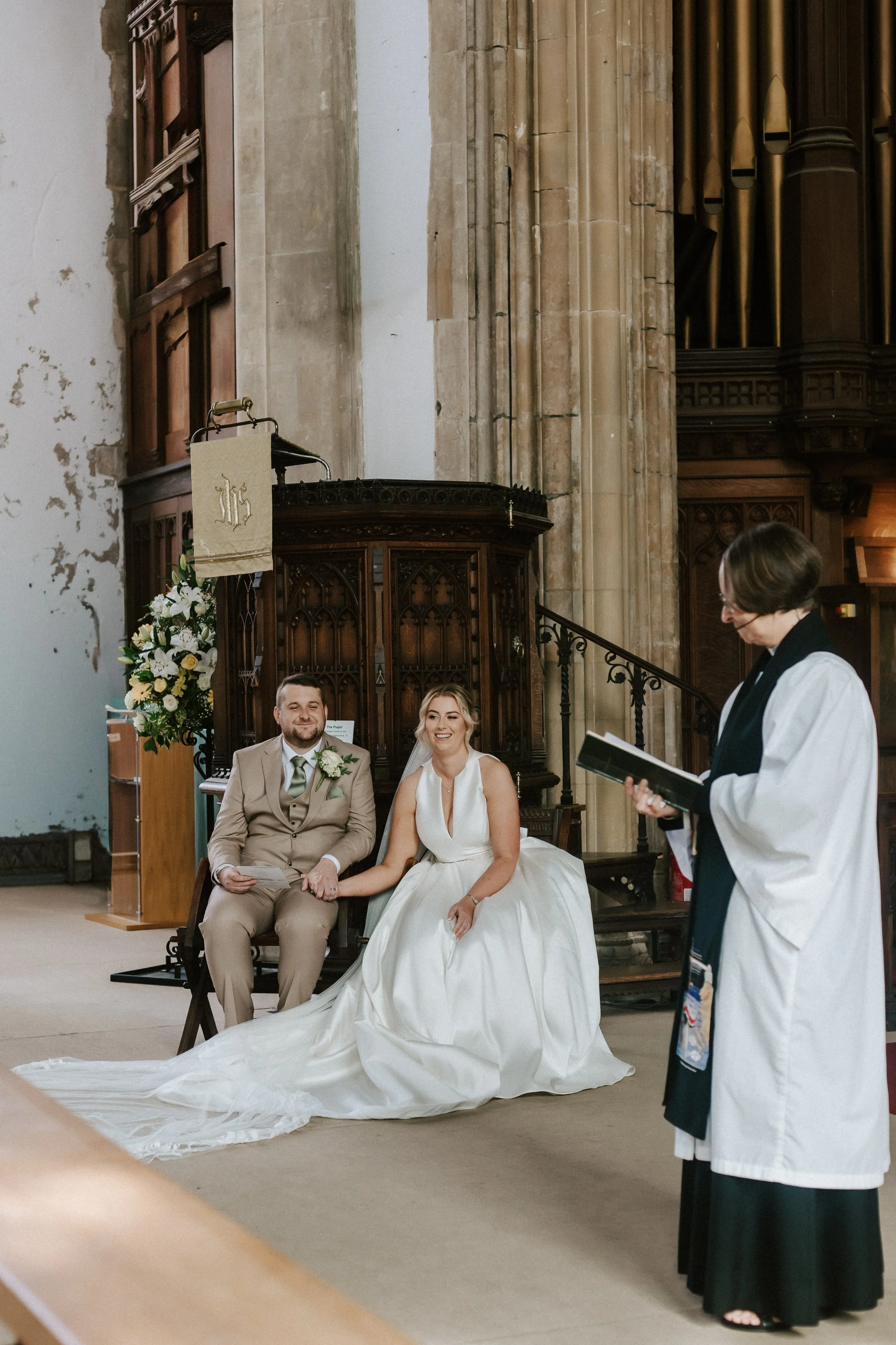 Documentary wedding photographer Suffolk and Norfolk β bride and groom holding hands during church ceremony with minister