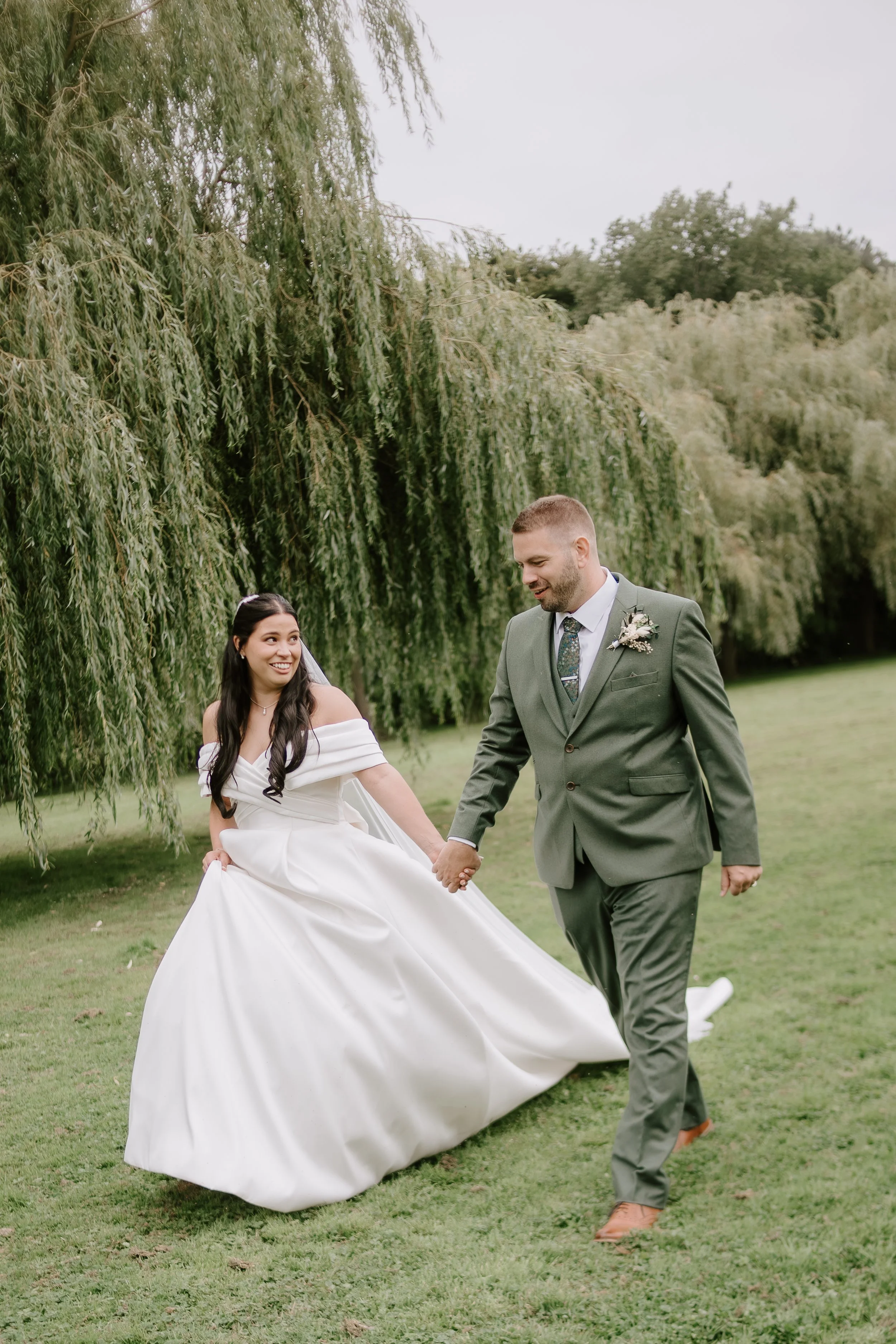 Natural and relaxed wedding photographer Suffolk and Norfolk β bride and groom walking hand in hand outdoors with lush greenery