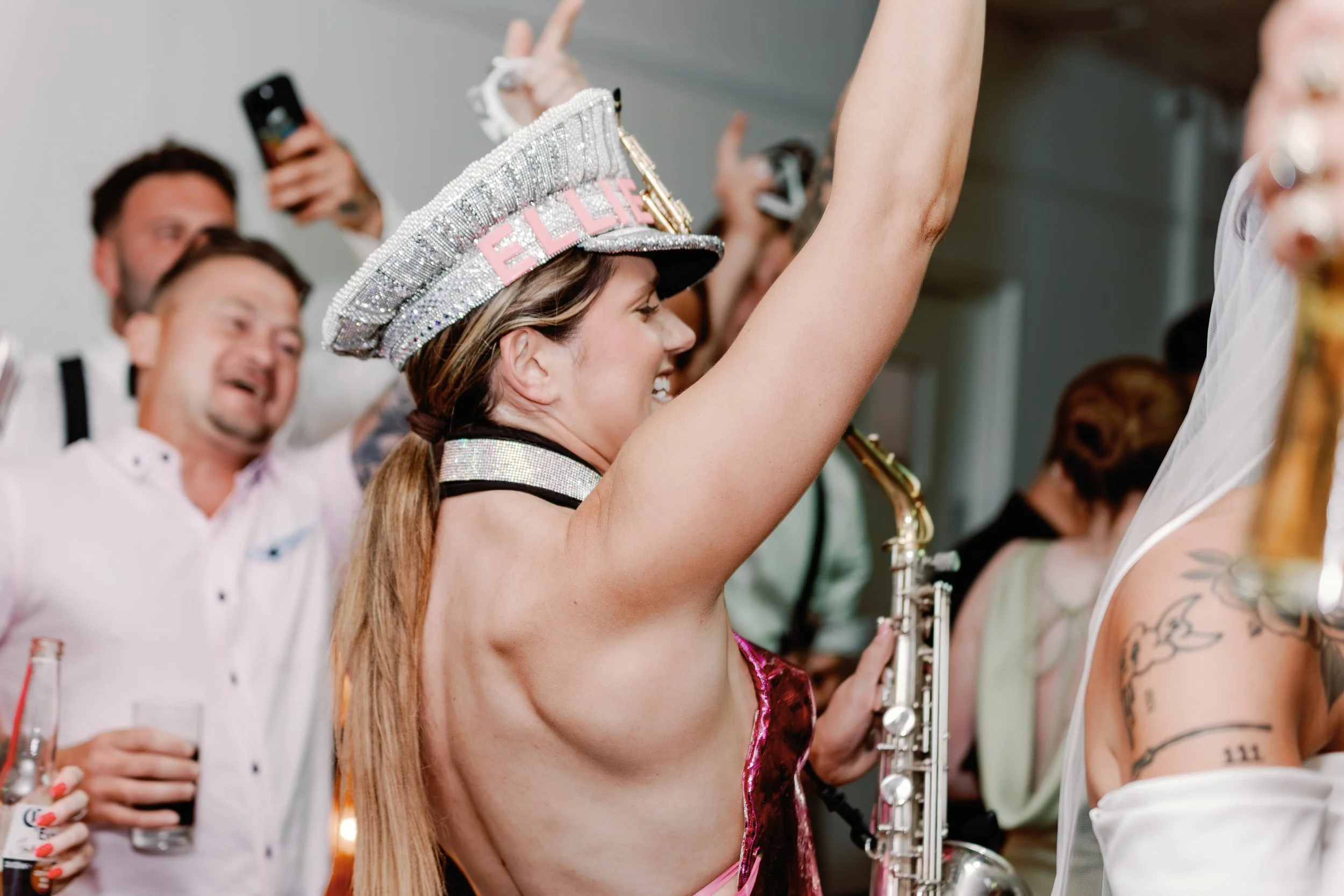 Live saxophonist Elllie Sax performing on the dance floor at a stylish Suffolk wedding, surrounded by guests capturing the moment — perfect for couples seeking unforgettable wedding entertainment and vibrant photography.
