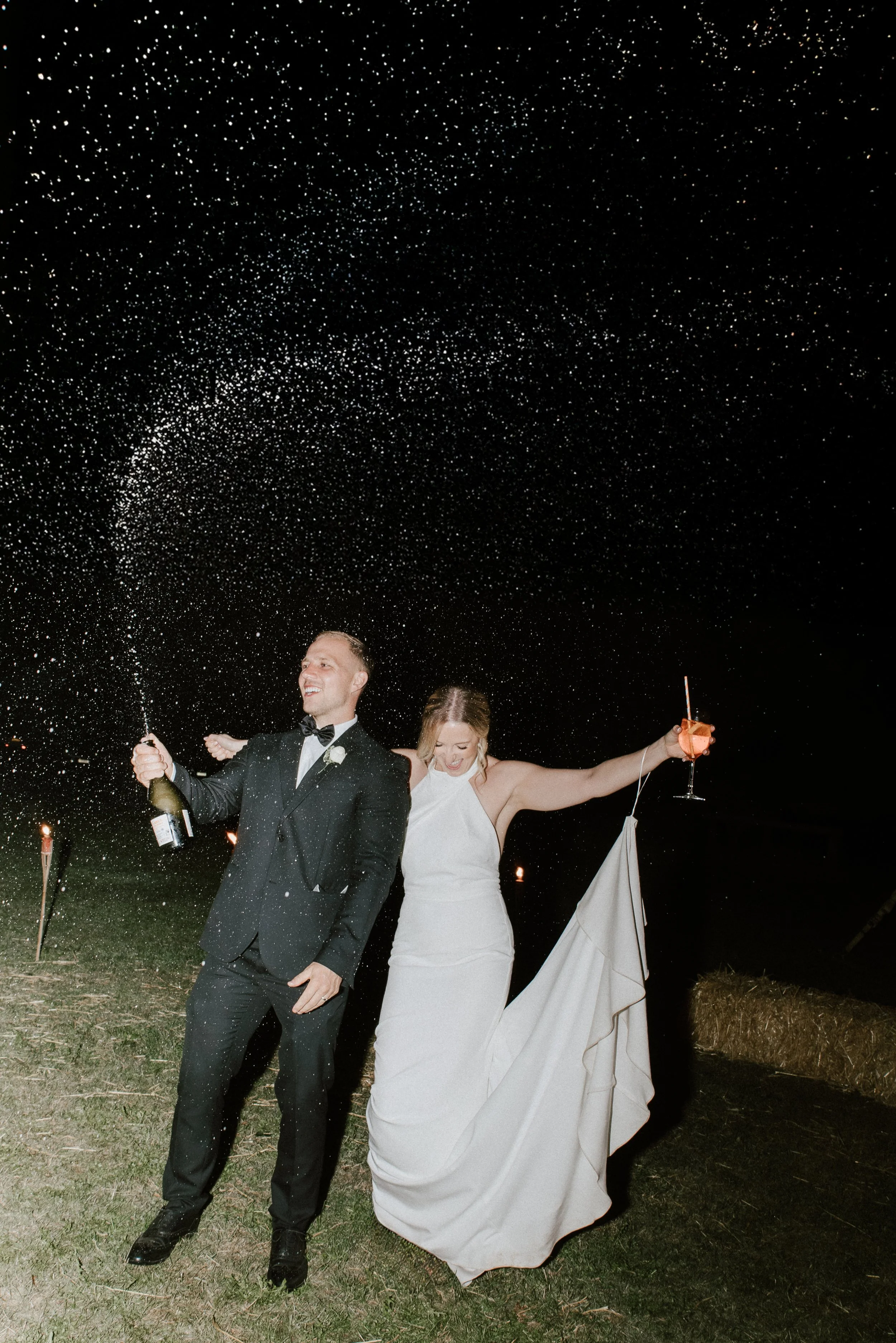 Elegant and candid wedding photographer Suffolk and Norfolk – newlywed couple celebrating outdoors at night with sparklers and drinks