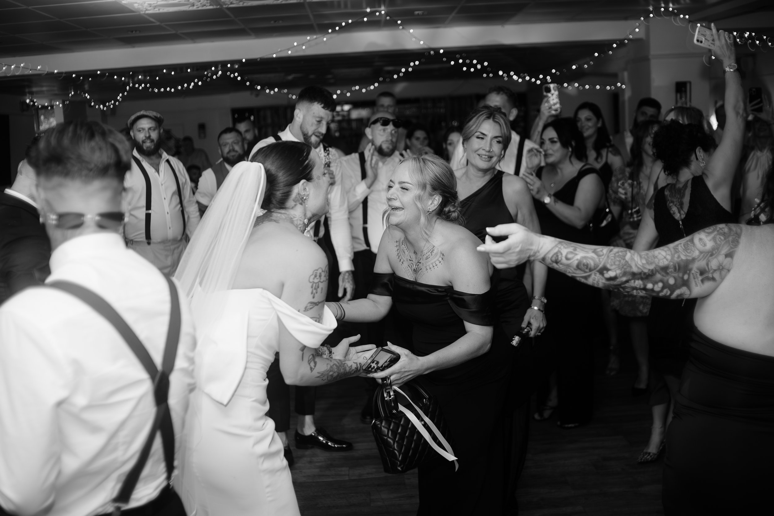 Bride laughing with bridesmaid during evening wedding reception at Suffolk venue – candid emotional moment captured by documentary wedding photographer.