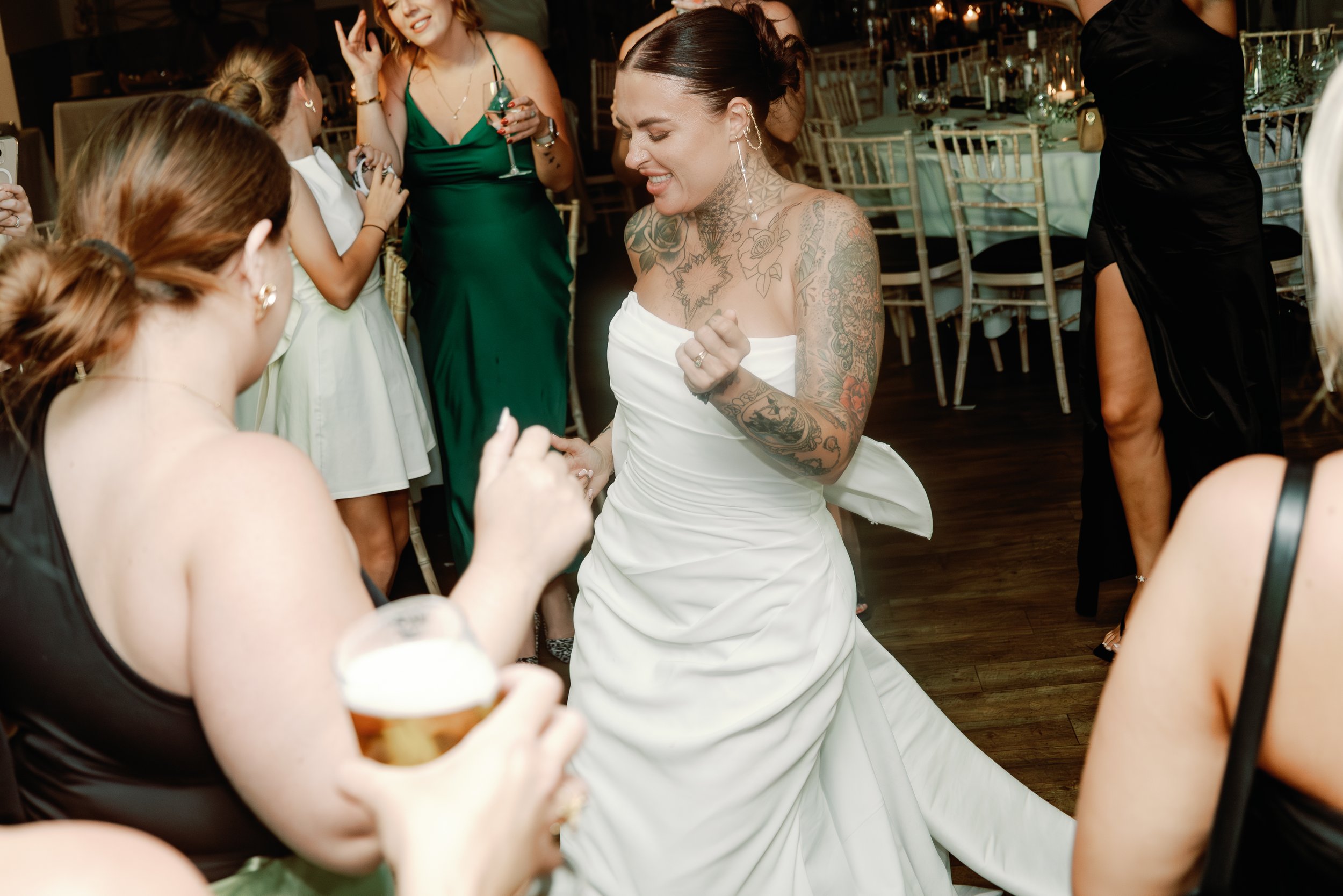 bride dancing with guests during lively evening reception at modern Suffolk wedding, captured by documentary-style UK wedding photographer.