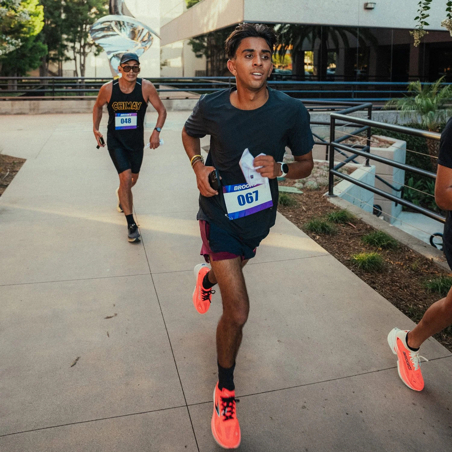 Shadow Strike runner sprints away from a checkpoint in Brea, CA, with another participant close behind during the Unsanctioned Race.