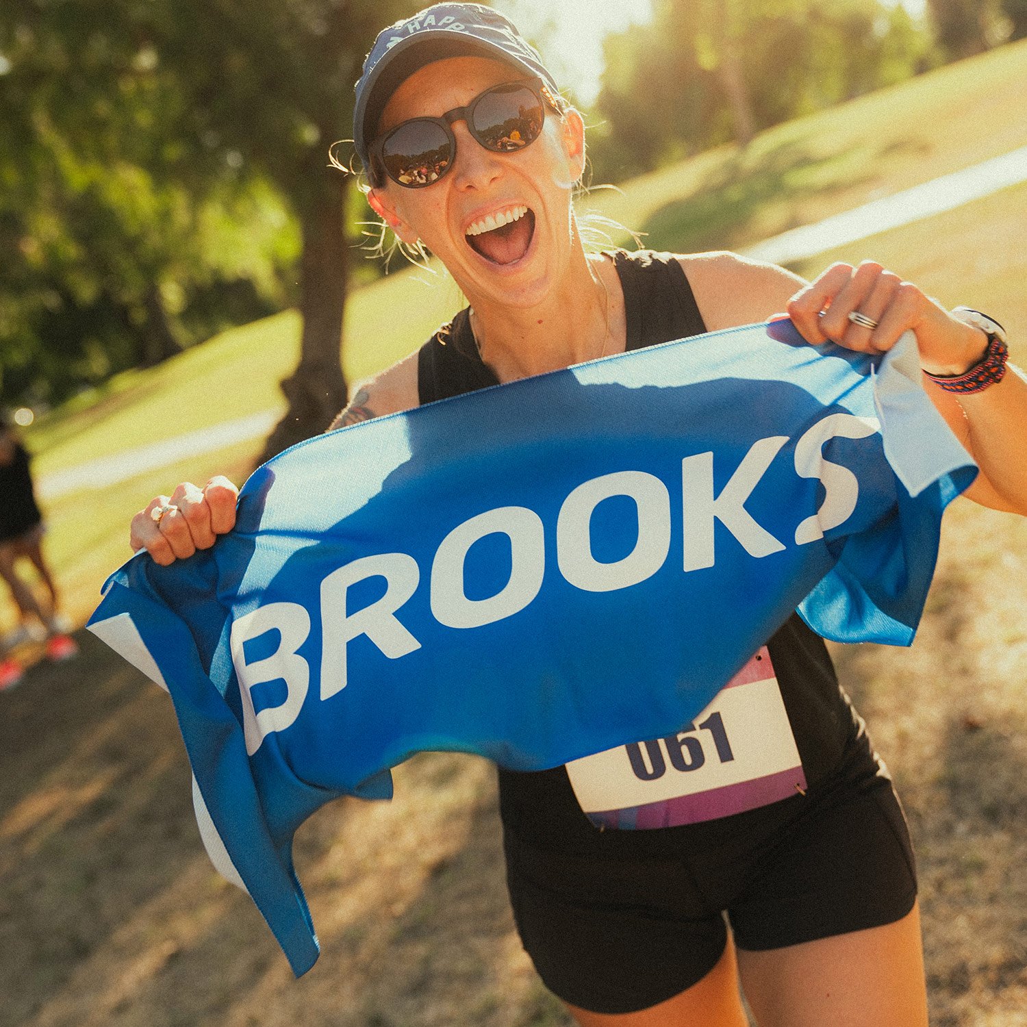 Shadow Strike participant holds a Brooks banner and cheers alongside fellow runners during the Unsanctioned Race in Brea, CA.
