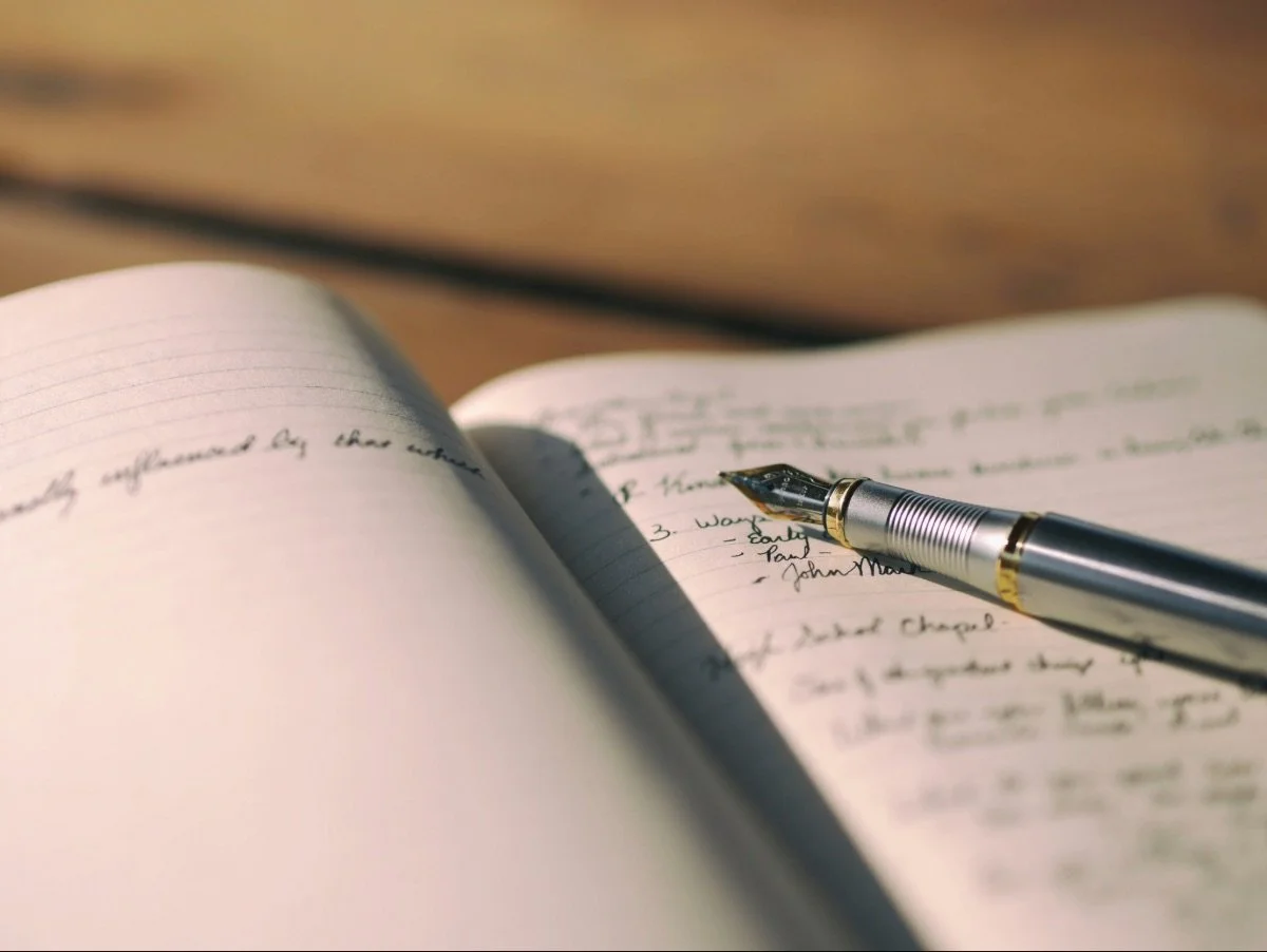 Handwritten pages in an open notebook with a pen resting on them, a missionary's untold story written out