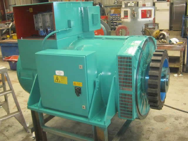 Industrial electric generator, teal color, in a workshop setting.