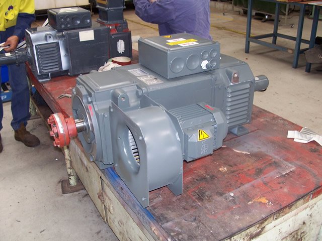 Industrial electric motor on a workbench in a workshop environment.