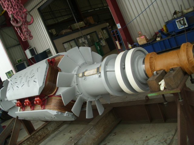 Large industrial rotor with copper windings and fins in a workshop setting