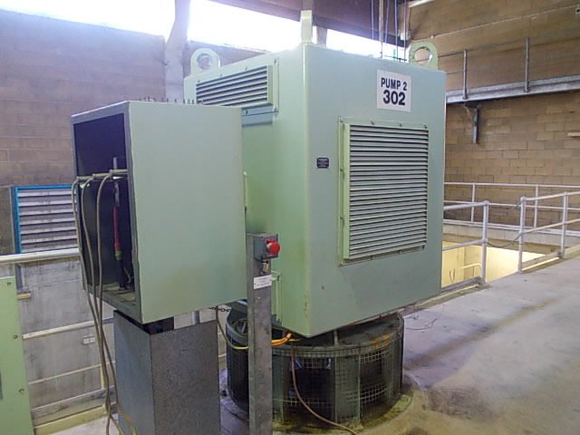 Industrial water pump labeled "Pump 2 302" in a facility, with cables connected to an adjacent control box.
