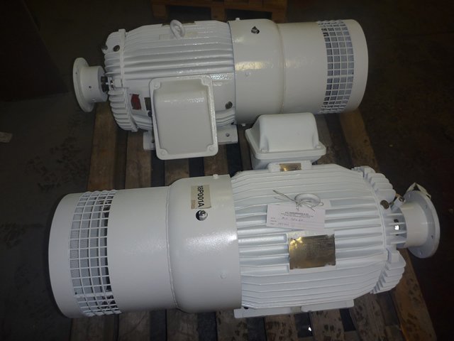 Two large white industrial electric motors on a wooden platform.