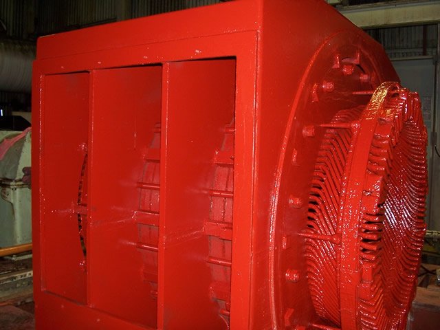 Large red industrial generator in a factory setting.