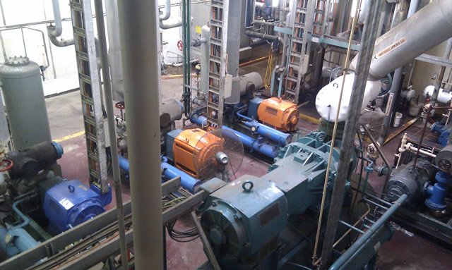 Industrial machinery setup with pumps, pipes, and motors in a mechanical room.