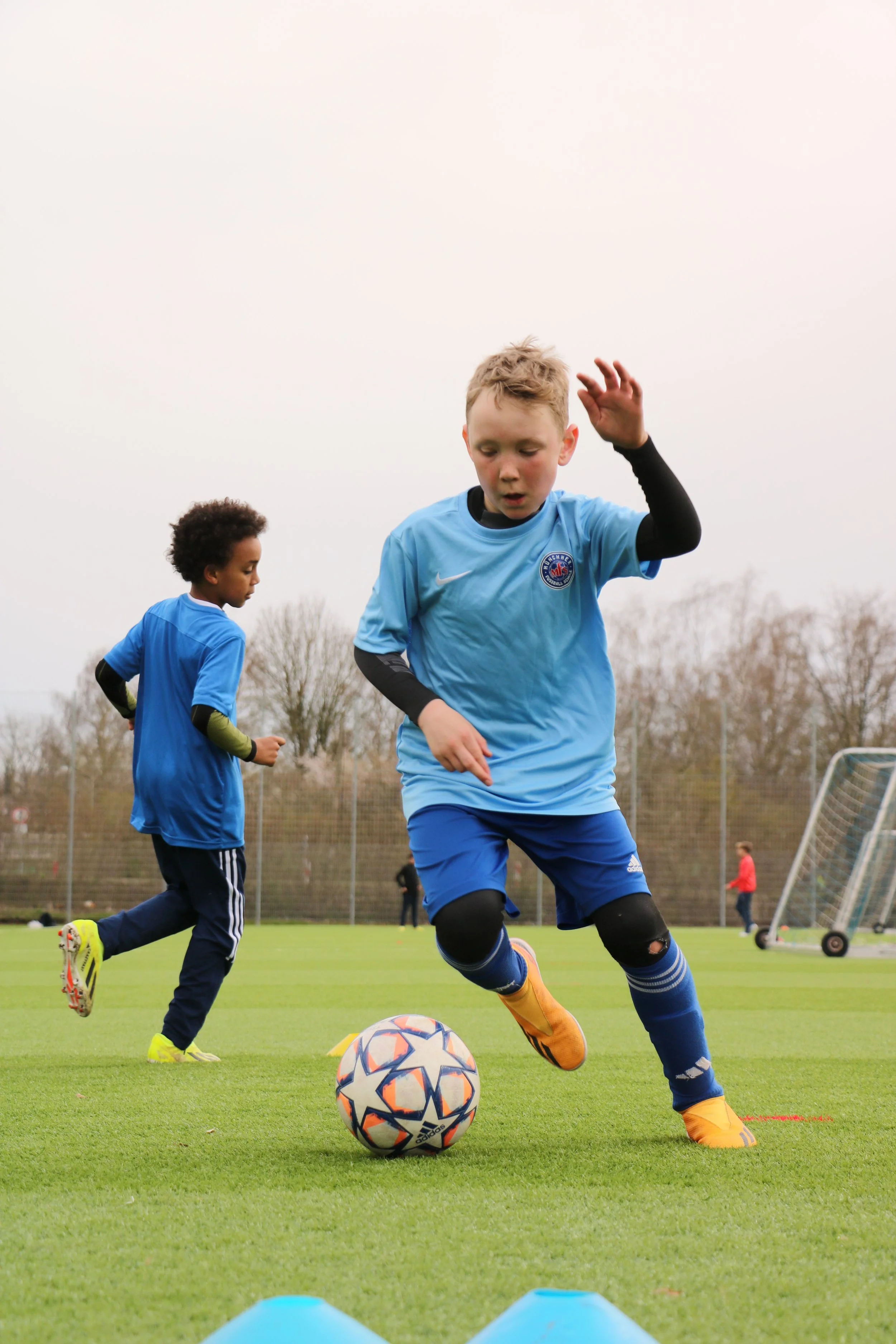 Ein Kind trainiert auf dem Fussballplatz der Münchner Fussball Schule Fussball.