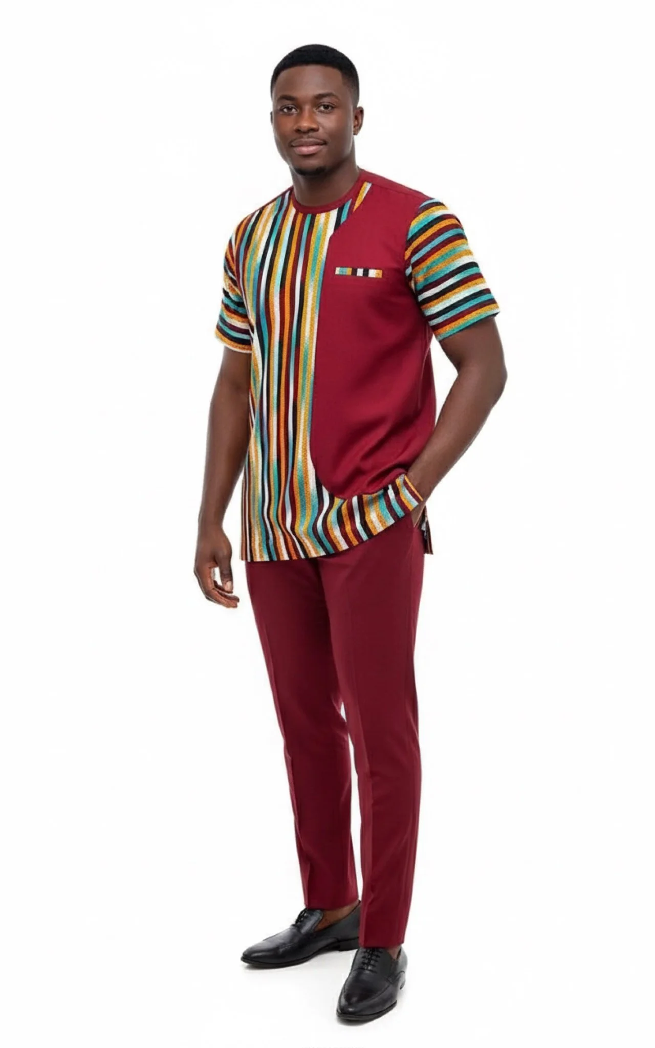A young man with short hair dressed in a colorful, patterned shirt with vertical stripes and solid maroon details, paired with maroon pants and black dress shoes, standing against a plain white background.