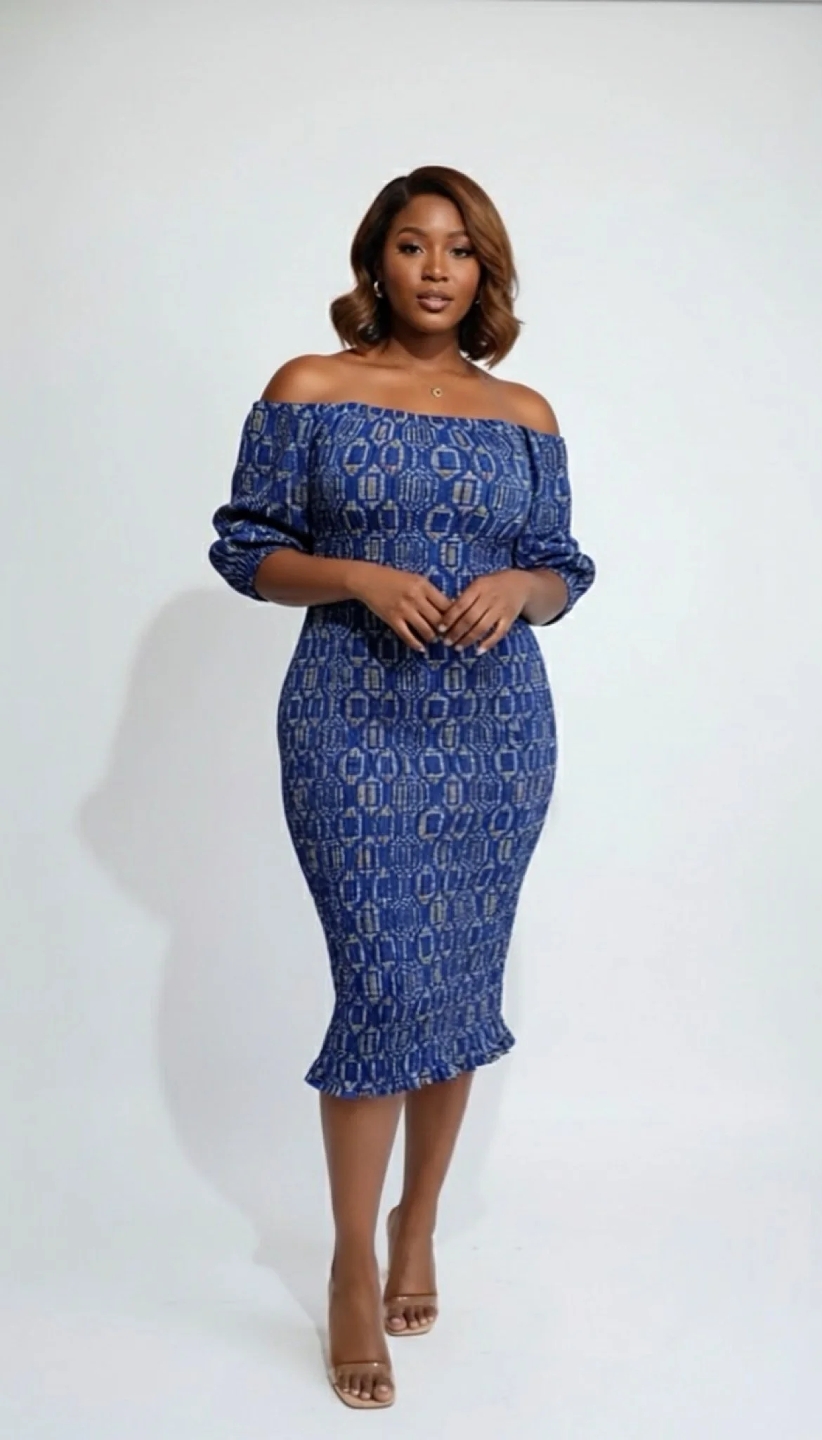 Woman in off-the-shoulder blue patterned dress posing against a plain white background.