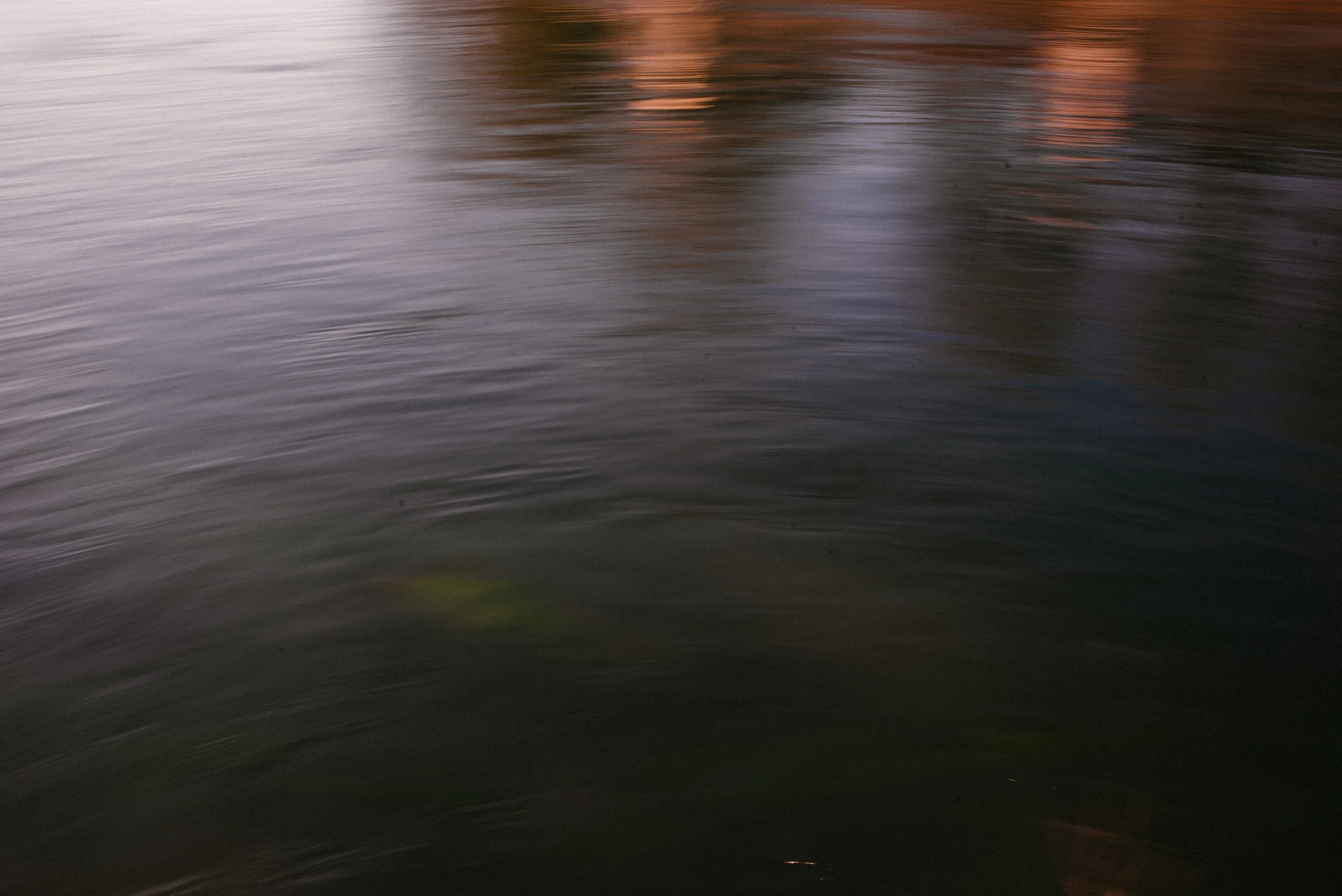 Calm water surface with gentle reflections of light and colors.