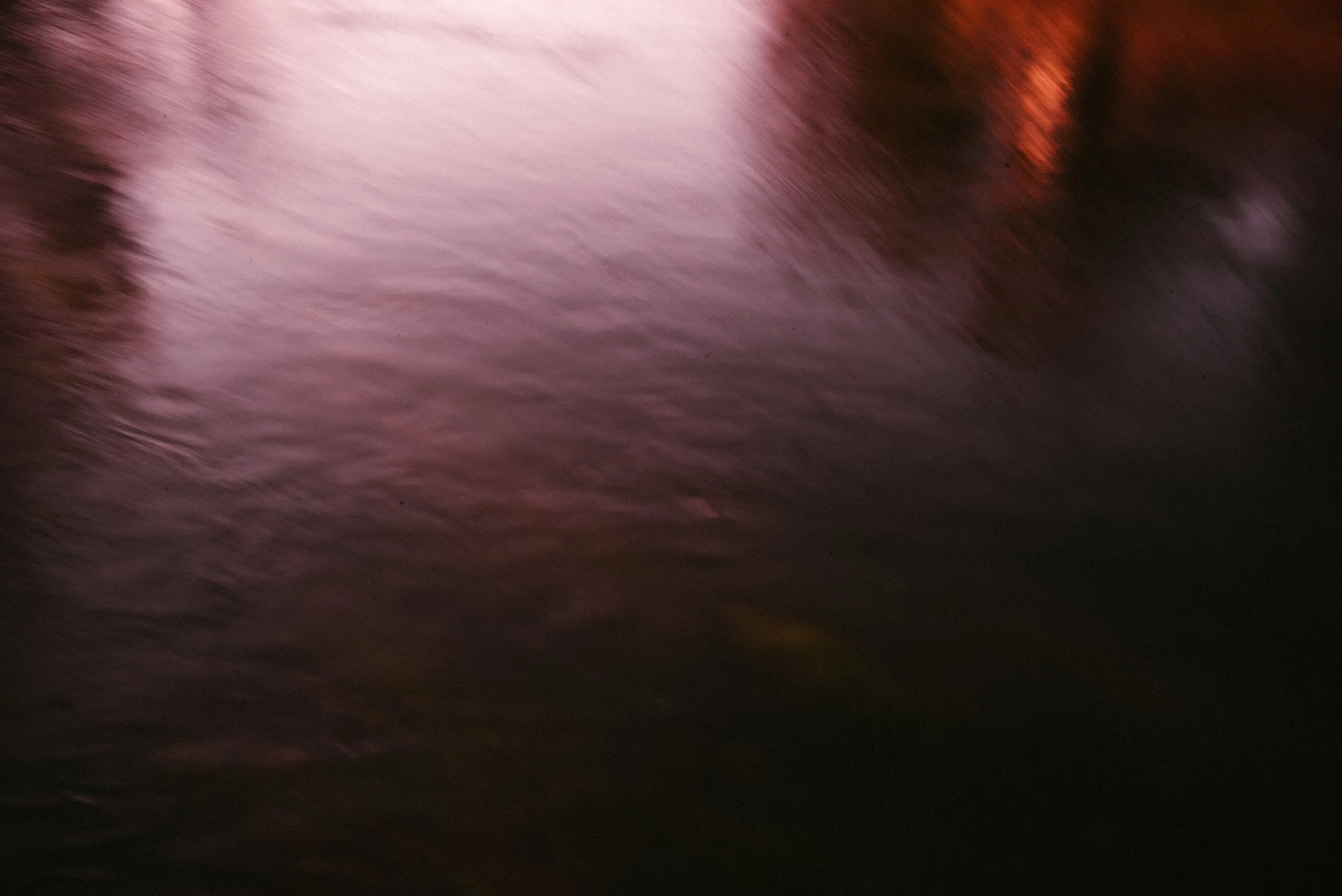 Blurred abstract reflection on water with red and purple hues.