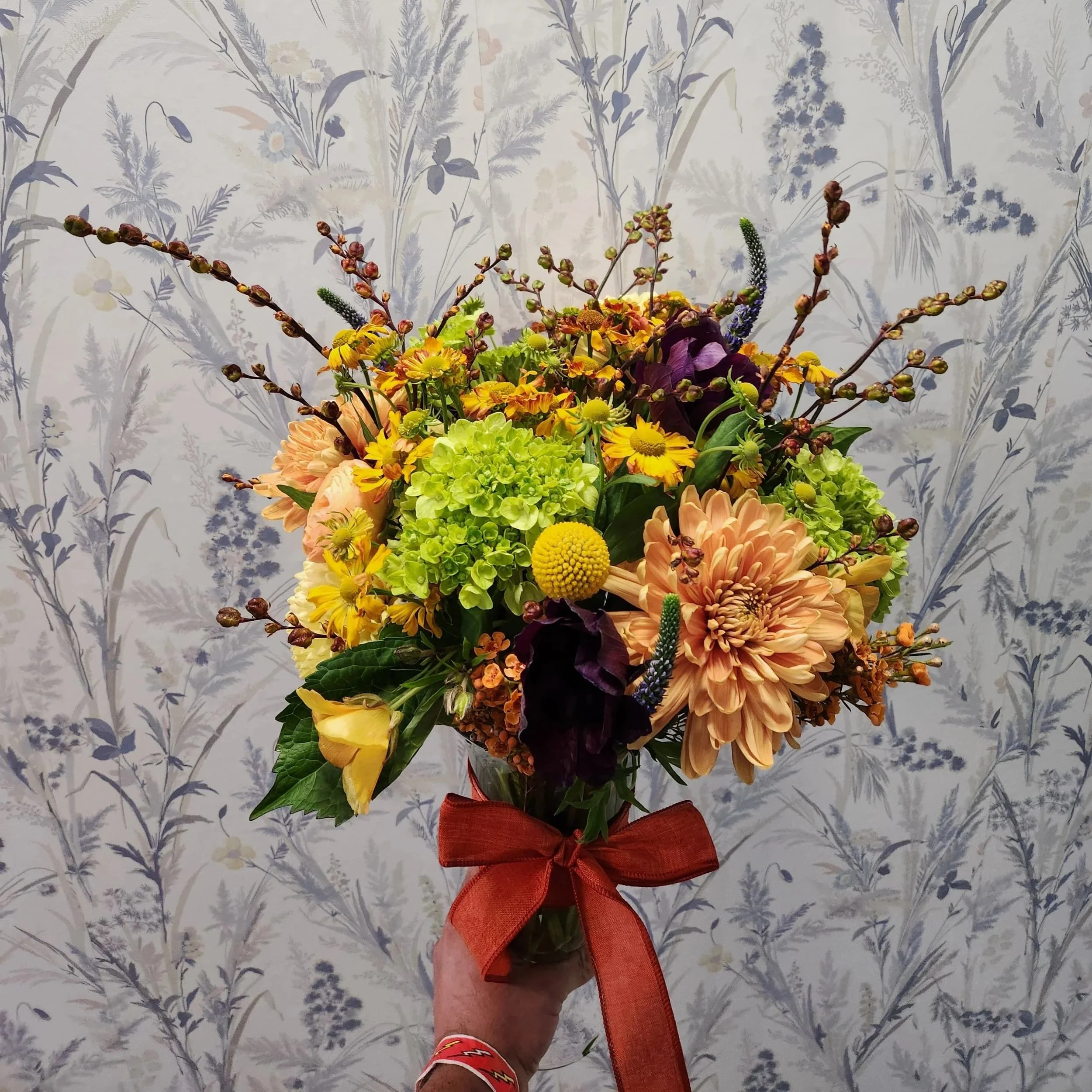 A bespoke, hand-tailored vibrant orange and deep red autumn arrangement by Quogue Flower Shop, perfect for your loved ones or a last-minute meaningful gift with same-day flower delivery across the Hamptons.