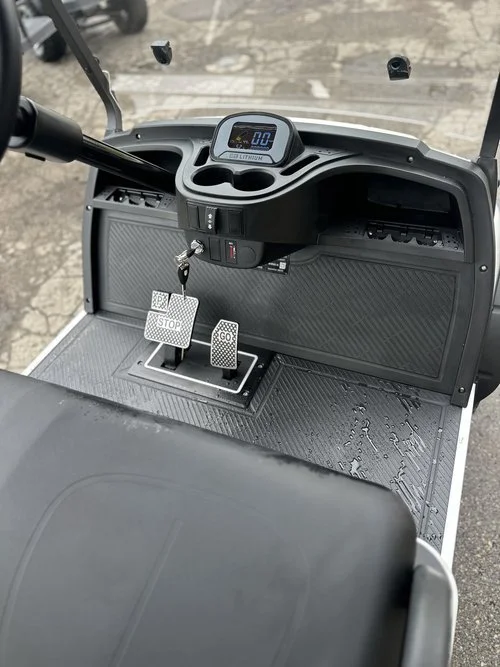 View of the control panel of a golf cart, showing a digital display, a key switch, and two pedals labeled 'STOP' and 'GO'.