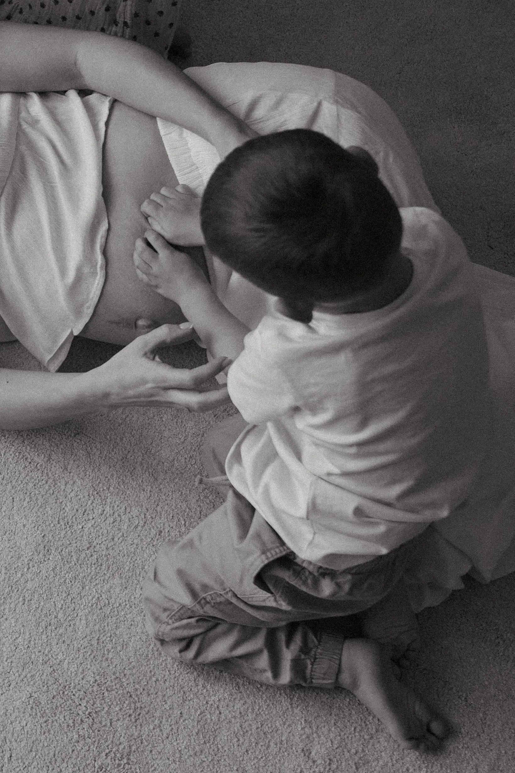 a young boy tickling his mothers belly 