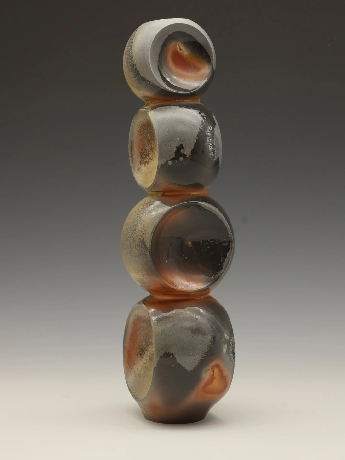 A vertical stack of four glass marbles with varied colors and textures, reflecting light against a dark gray gradient background.