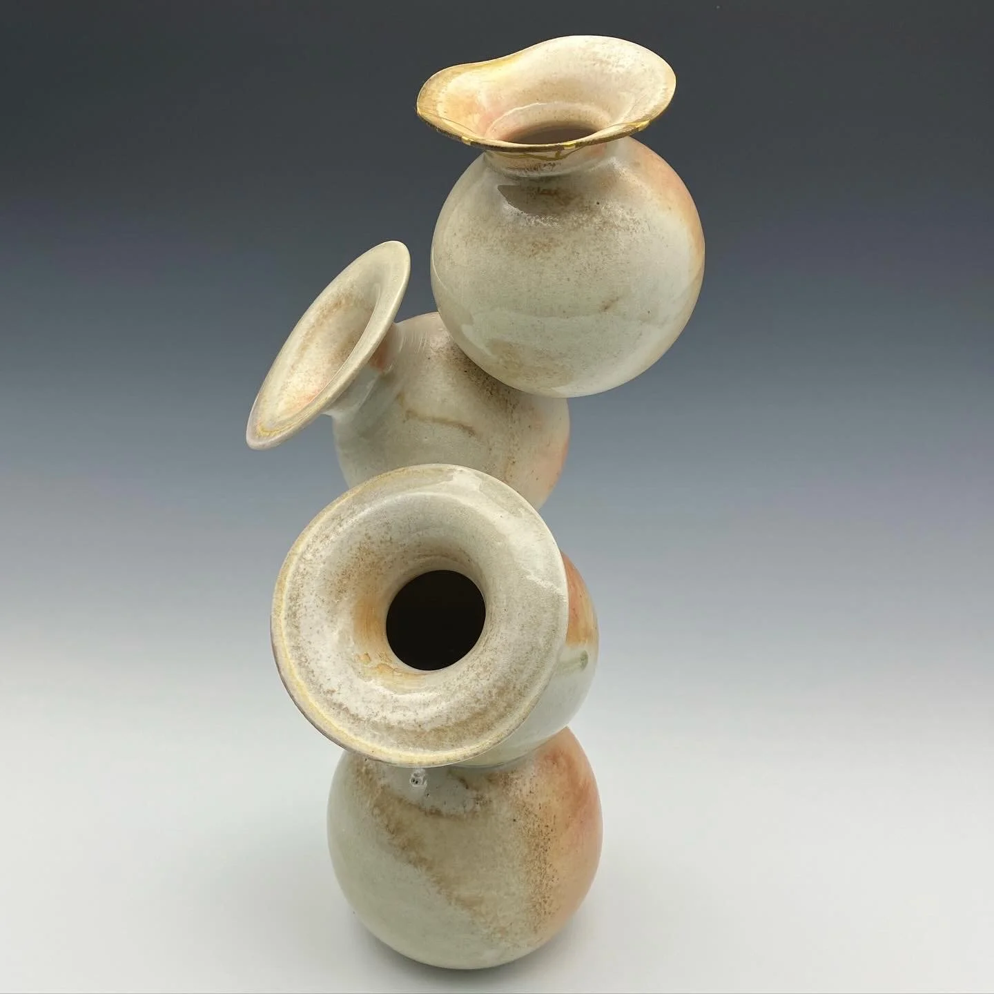 Stacked ceramic vases in earthy tones against a dark to light gradient background