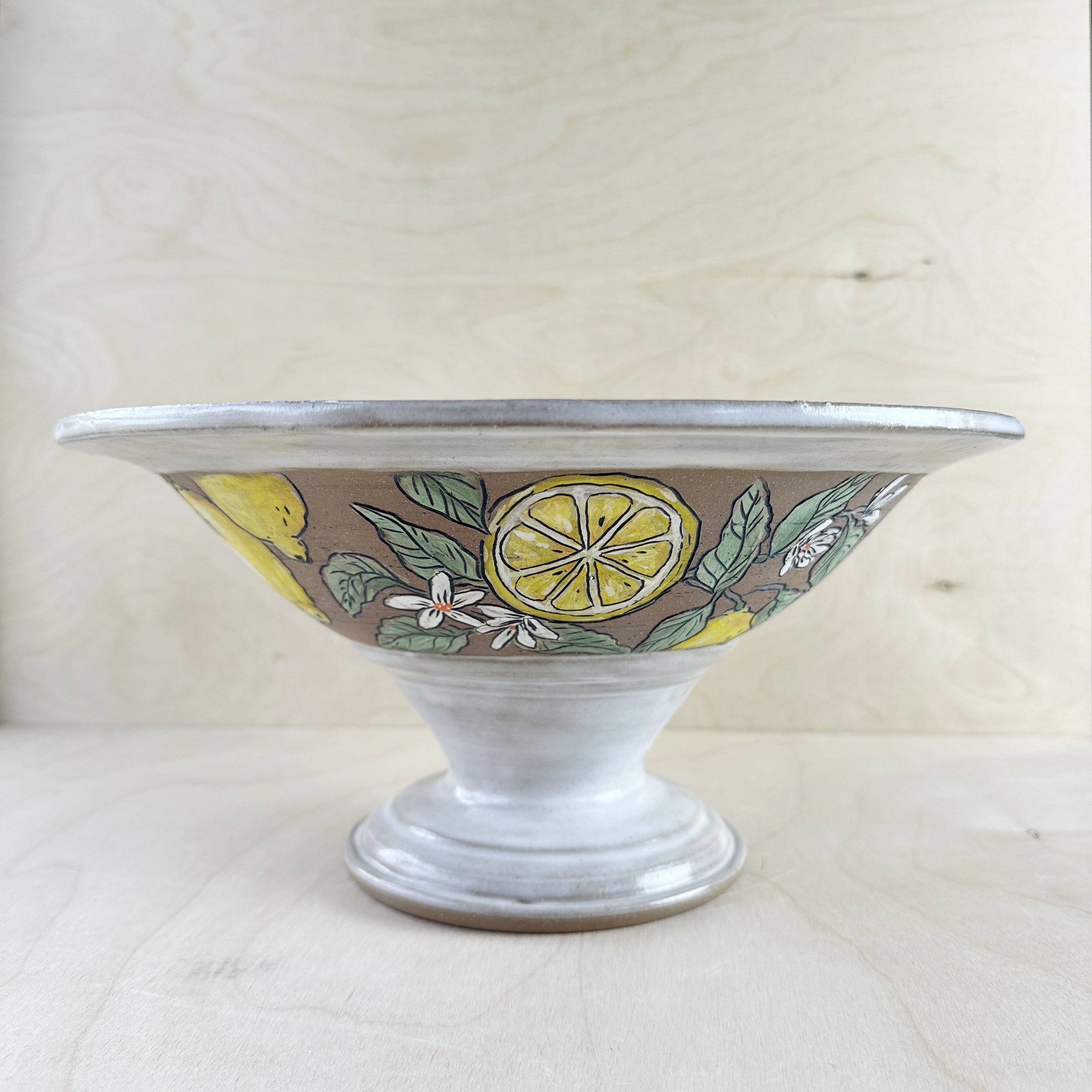 Decorative ceramic bowl with lemon and floral design on a wooden surface.